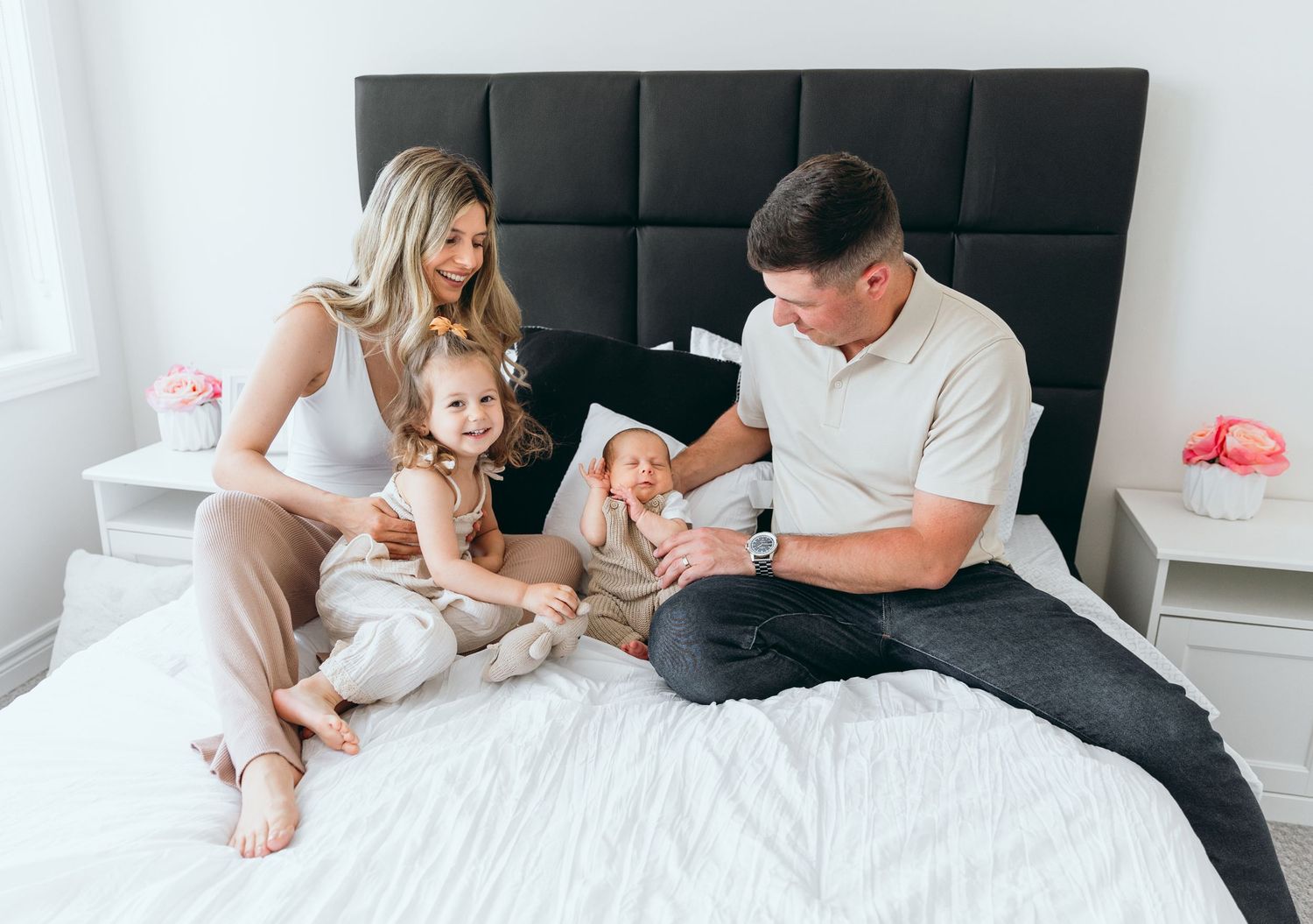 Family members sharing intimate moments on bed with black headboard.