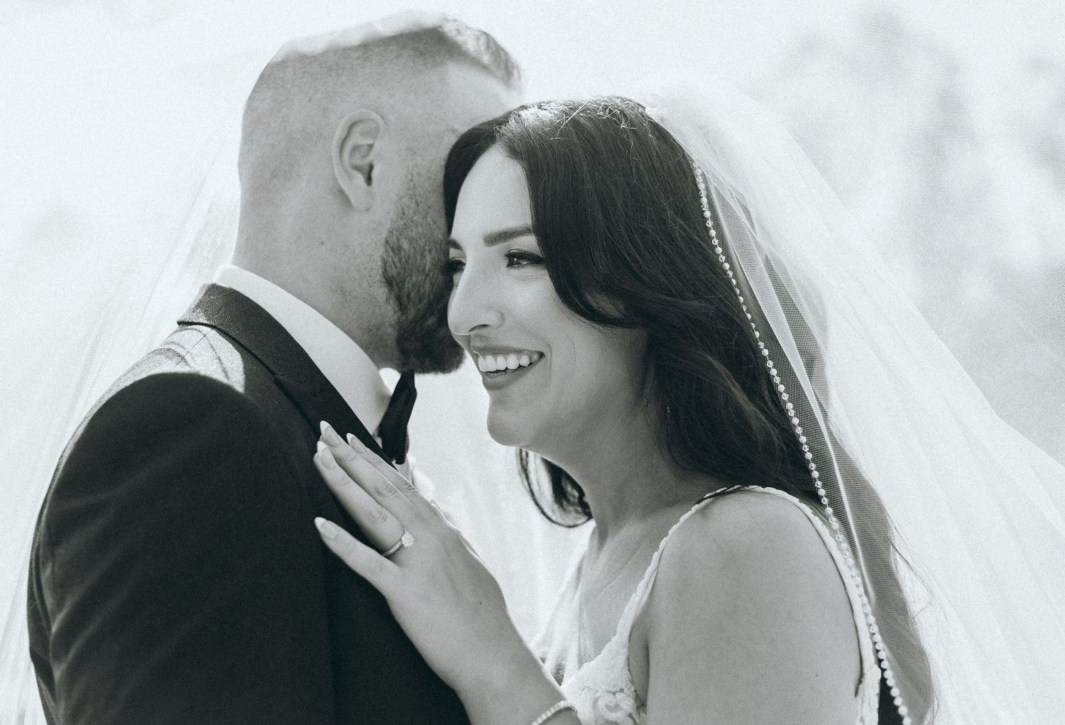 Black and white photo capturing joyful moment between couple during wedding ceremony.