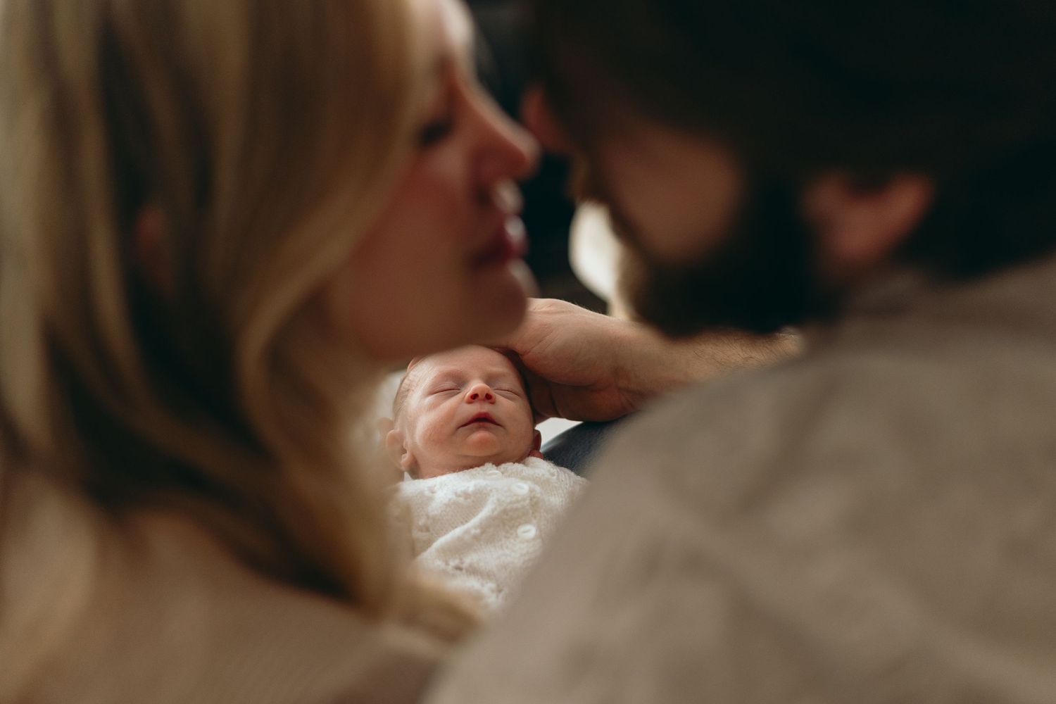 Intimate close-up photos in warm tones showing tender family interaction.