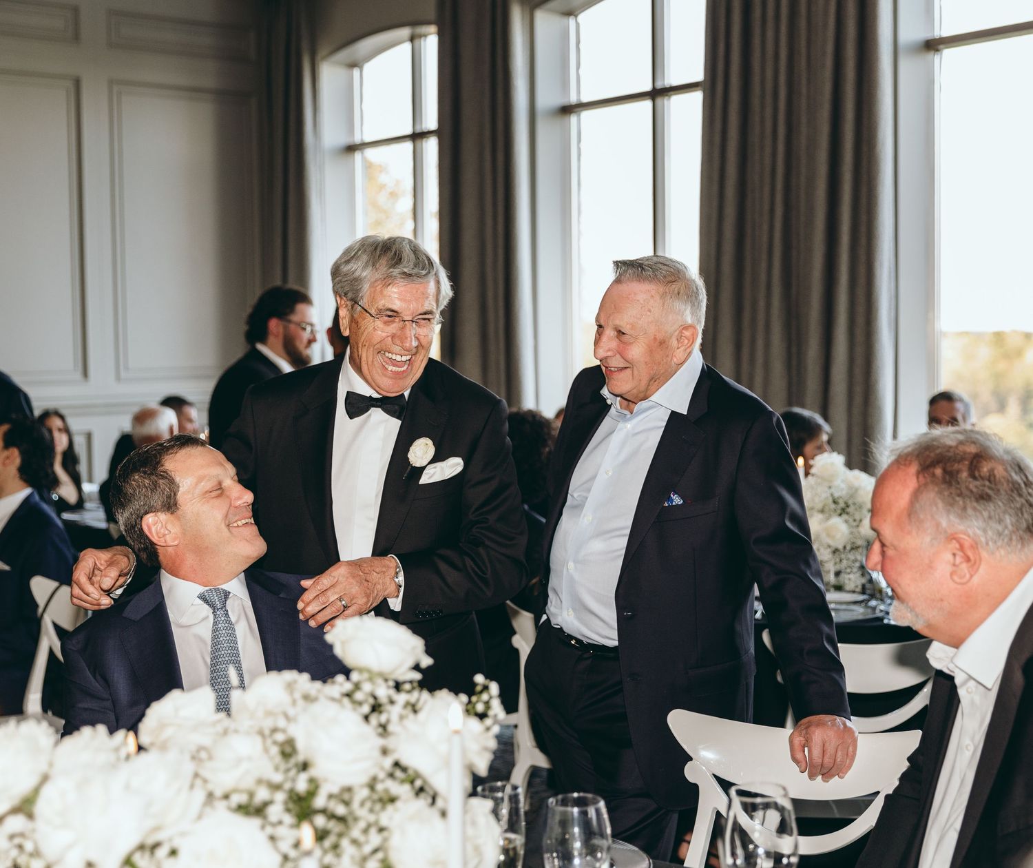 Formal gathering of guests in suits having animated conversation at elegant event.
