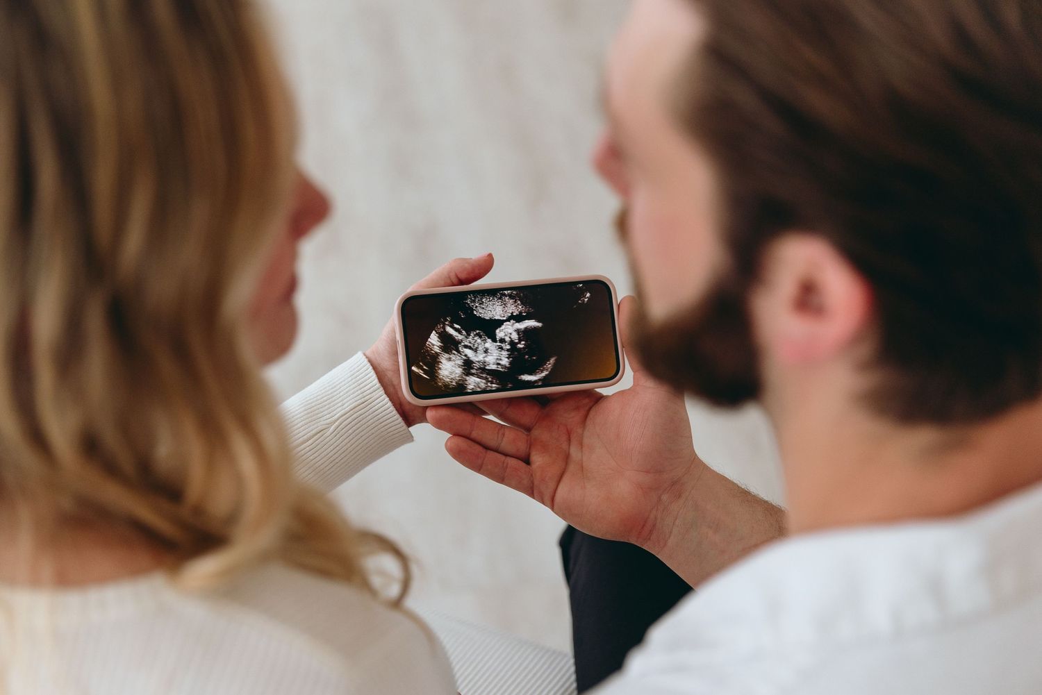 Close-up view of couple examining ultrasound image during pregnancy photoshoot.