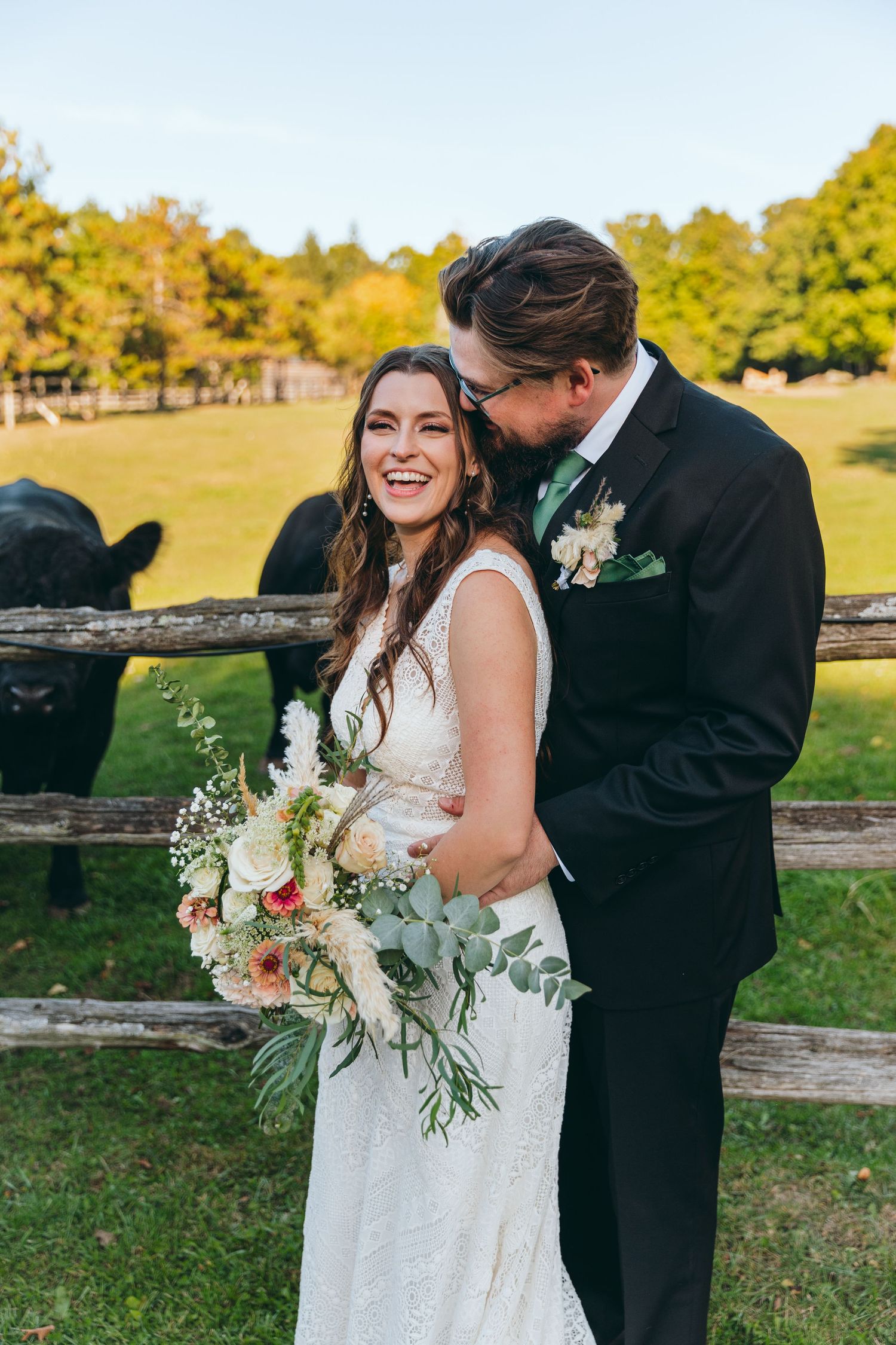 Couple shares intimate moments by a rustic wooden fence during golden hour.