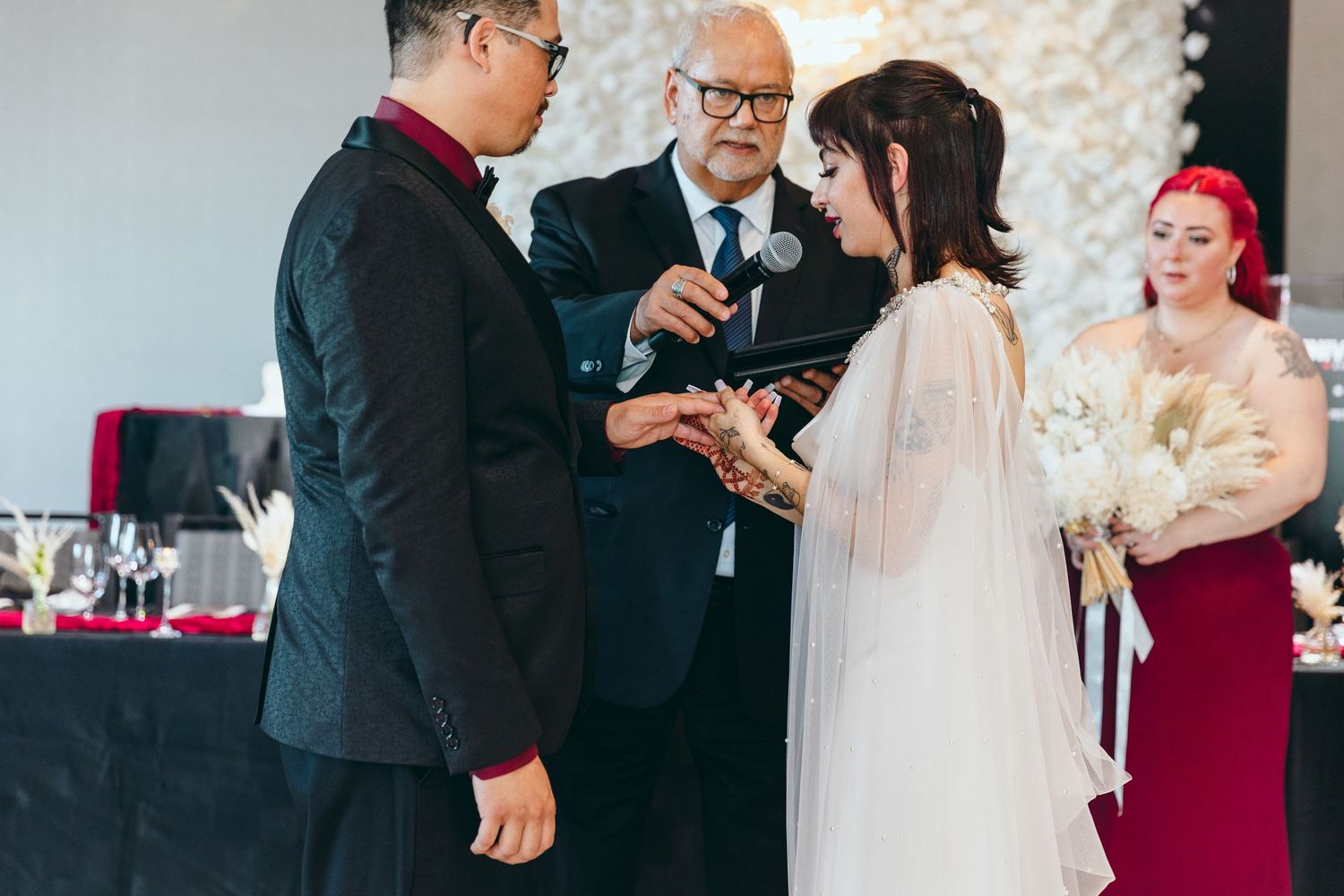 Candid wedding ceremony moments with guests in formal attire against a white floral backdrop.