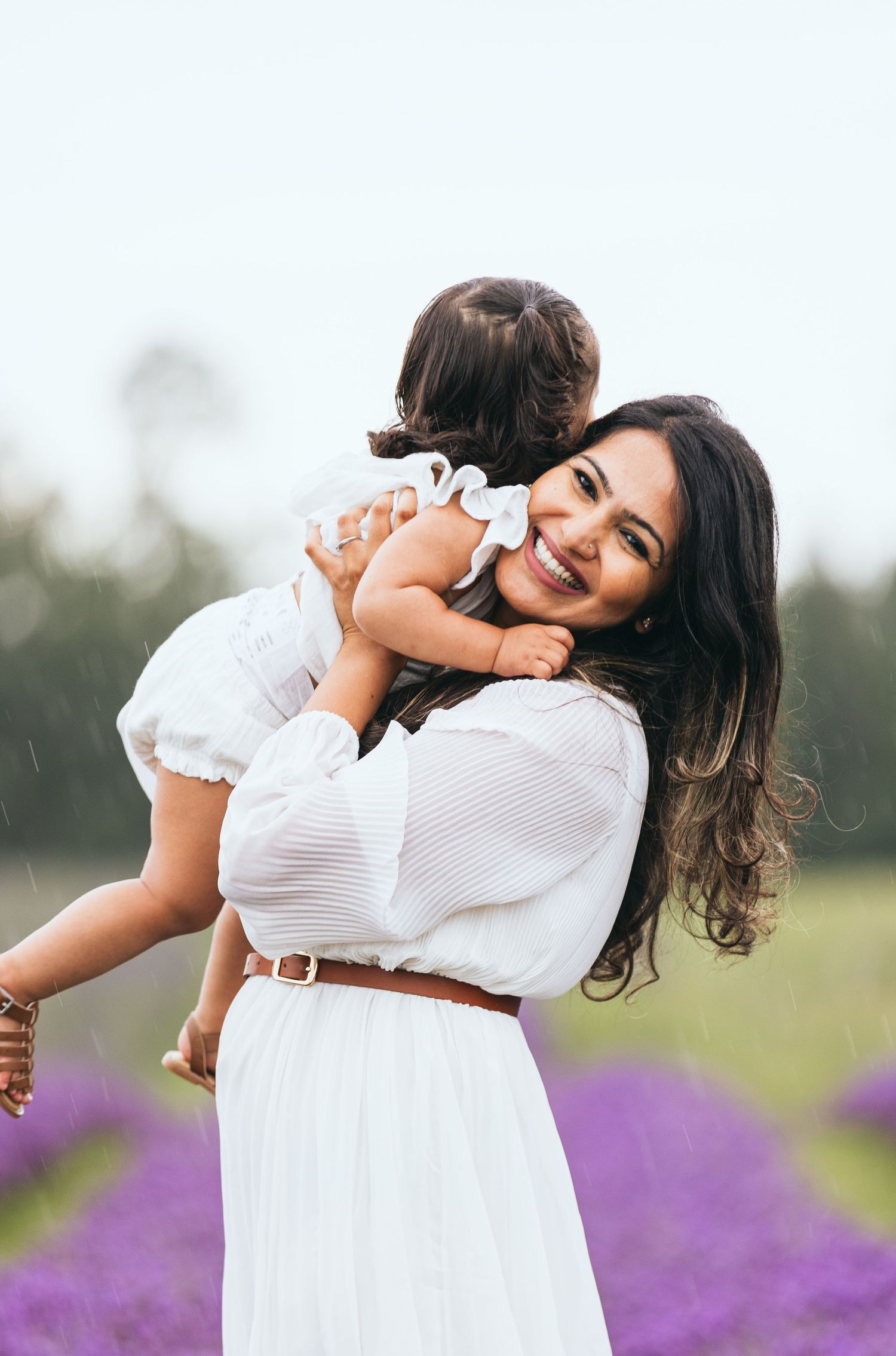 Two people sharing a joyful embrace in a field of purple flowers.