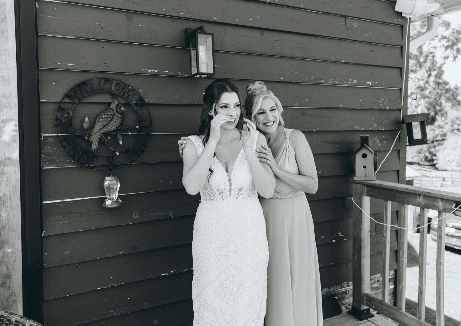 Black and white photo of two people embracing on a wooden porch.