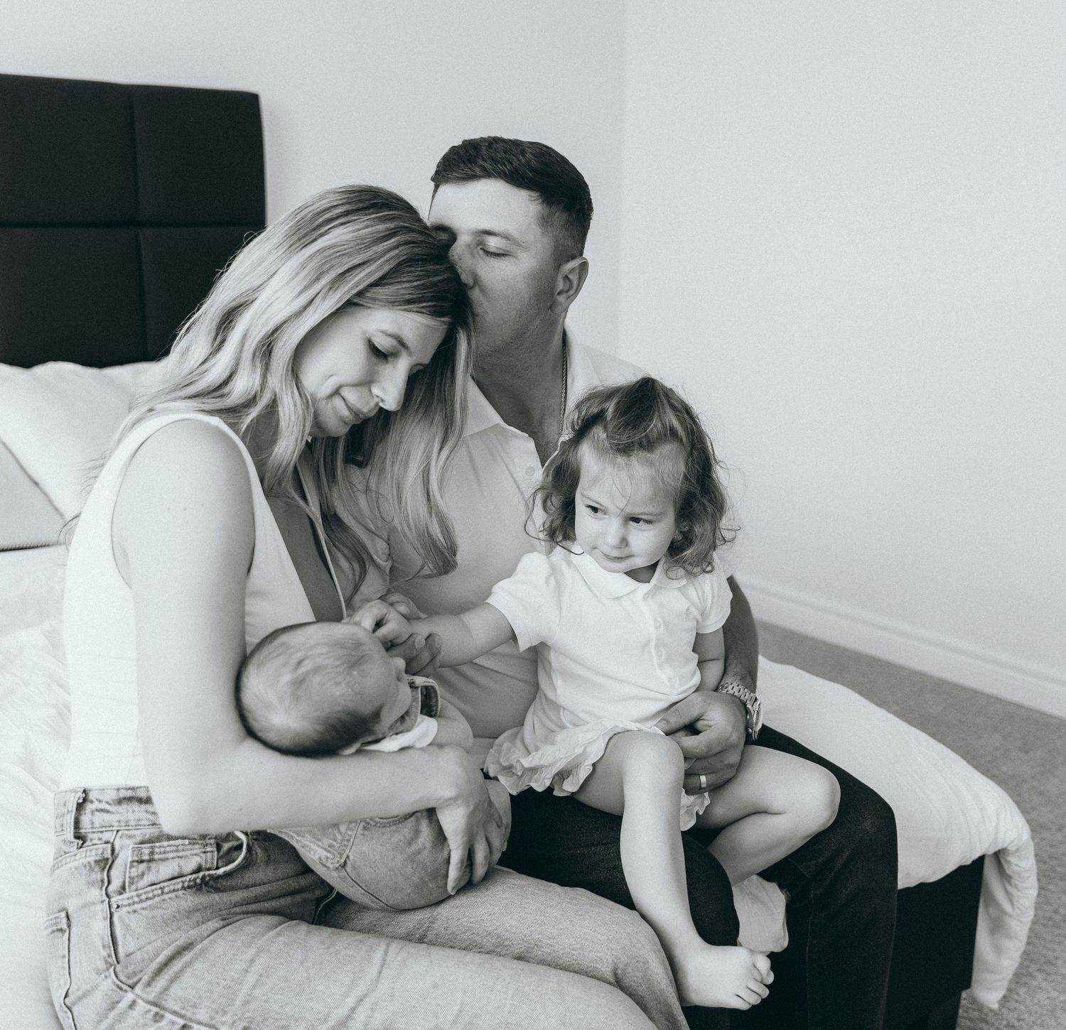 A family shares tender moments together on a light colored couch.