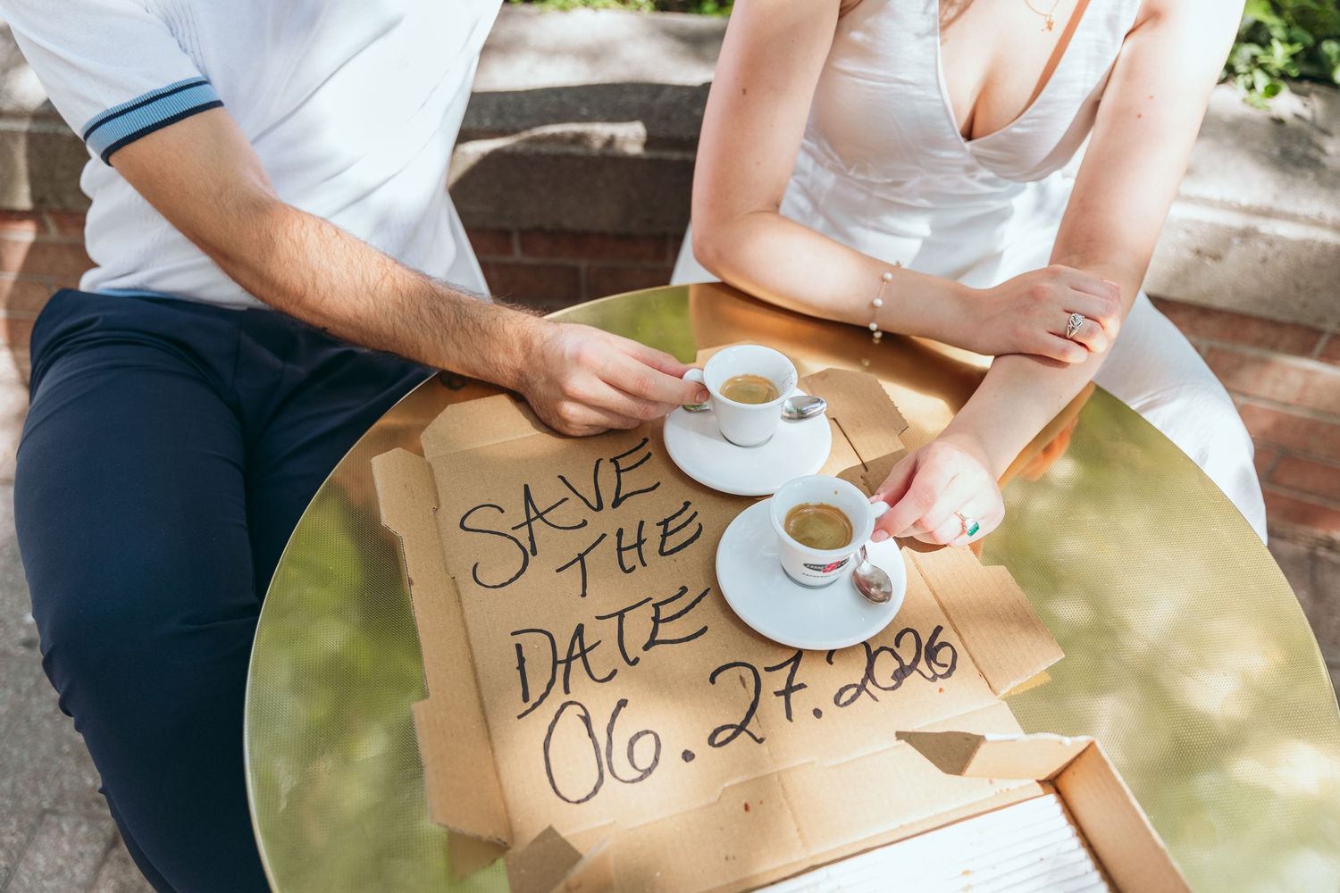 A couple sharing a meal at a round table with a save the date sign visible.