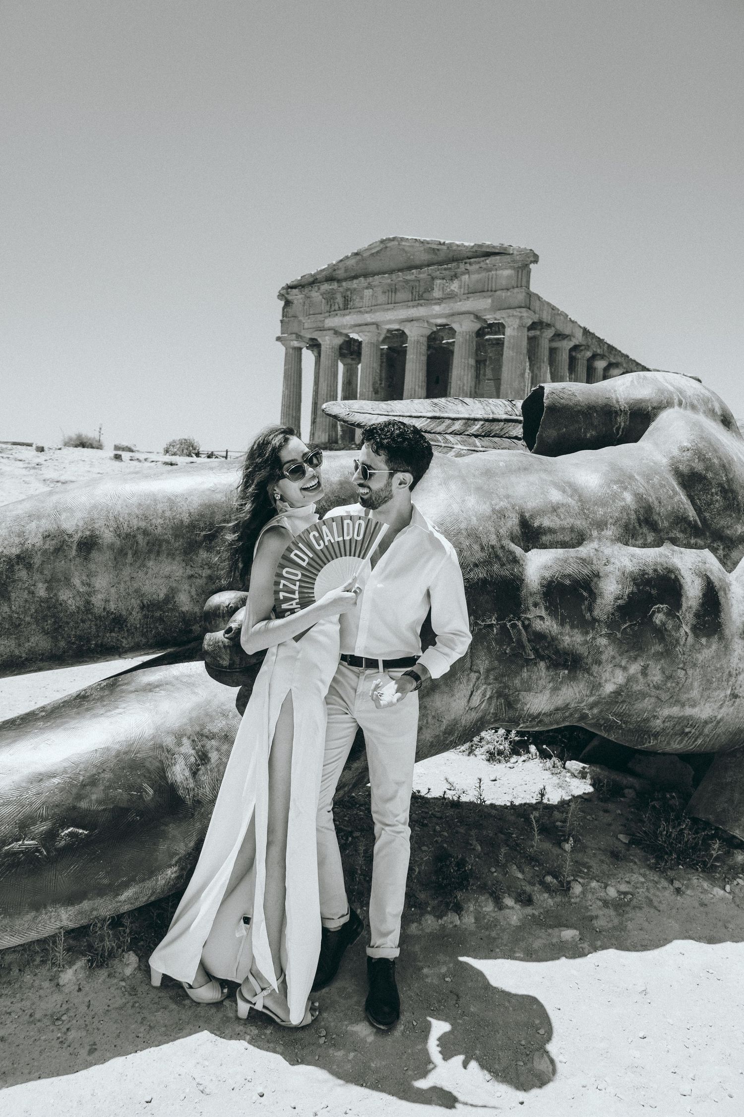 Two people in white outfits dance dramatically against ancient temple backdrop.