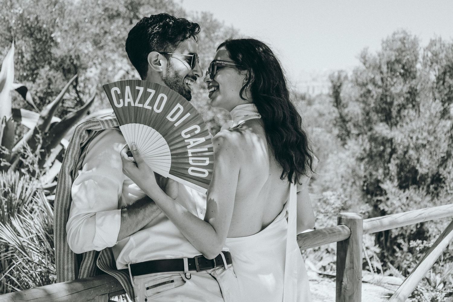 A romantic moment captured in black and white against a Mediterranean landscape.