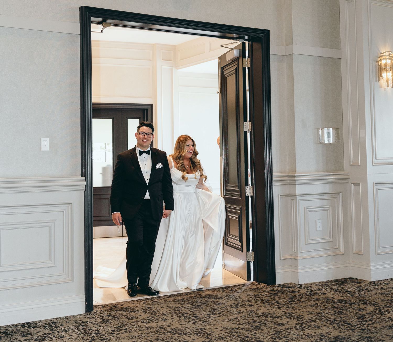 Wedding couple making their grand entrance through elegant double doors.