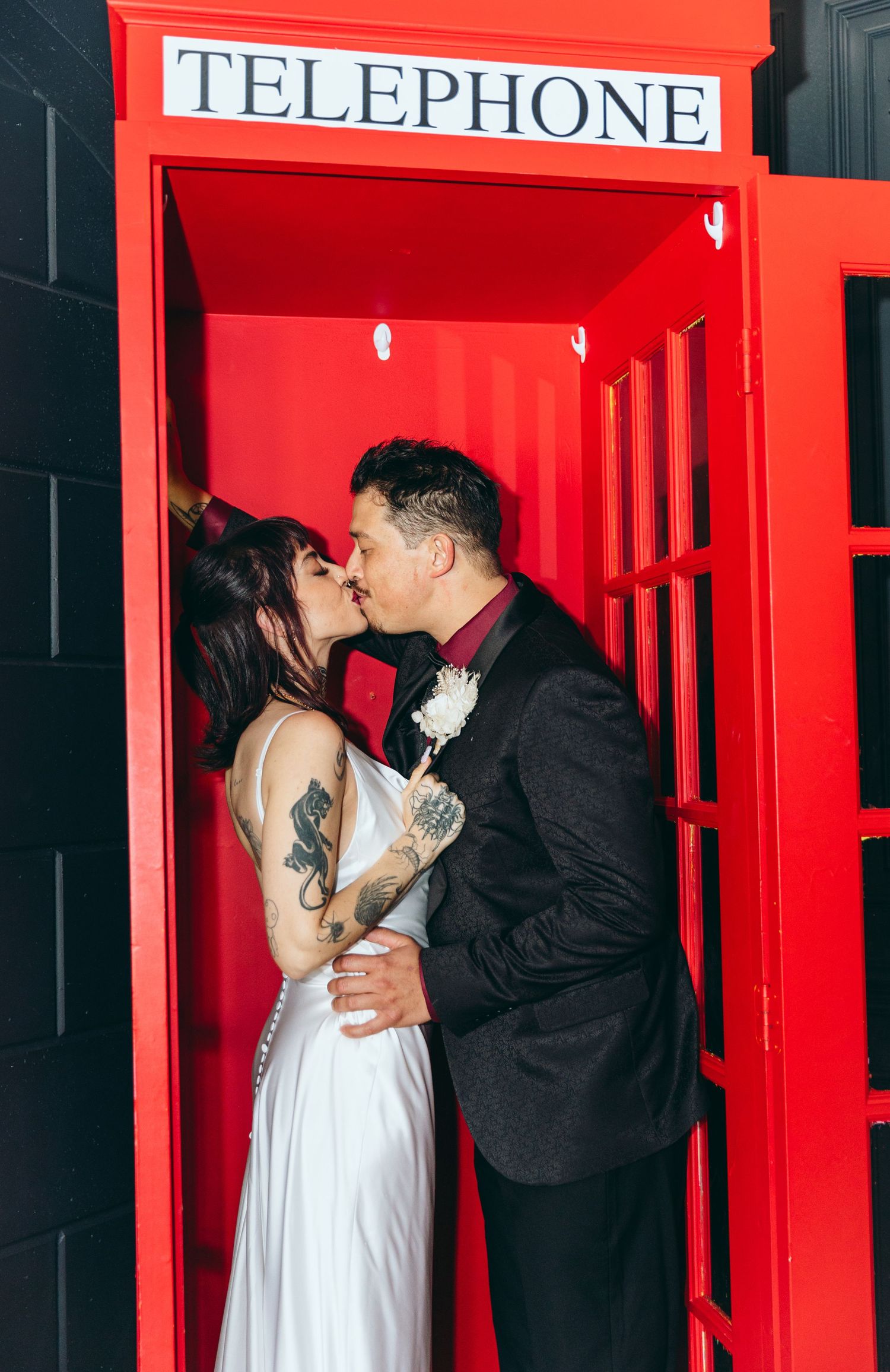 Couple shares romantic moment in vintage red telephone booth.