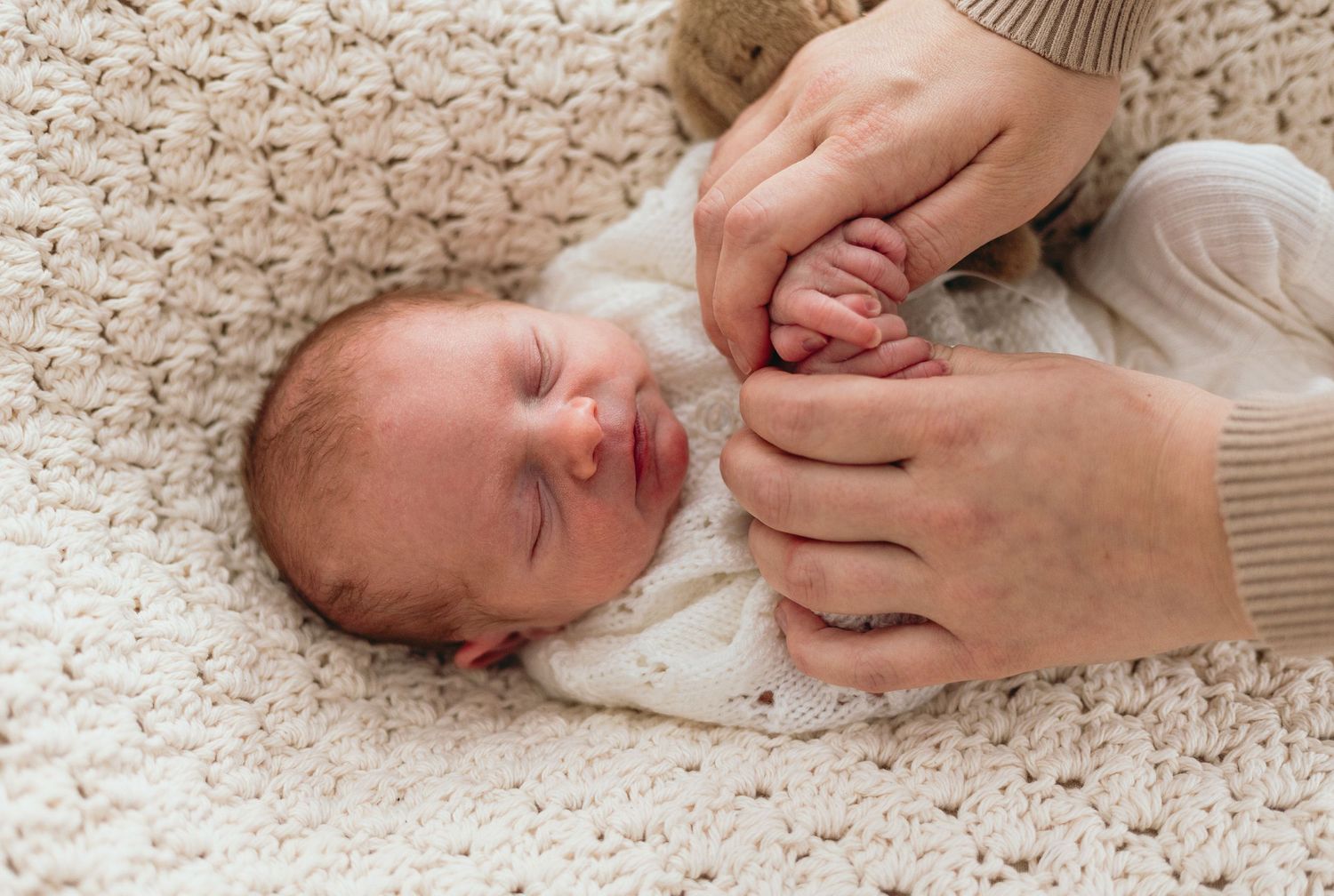 Close-up shots of a newborn baby resting on a cream-colored knit blanket.