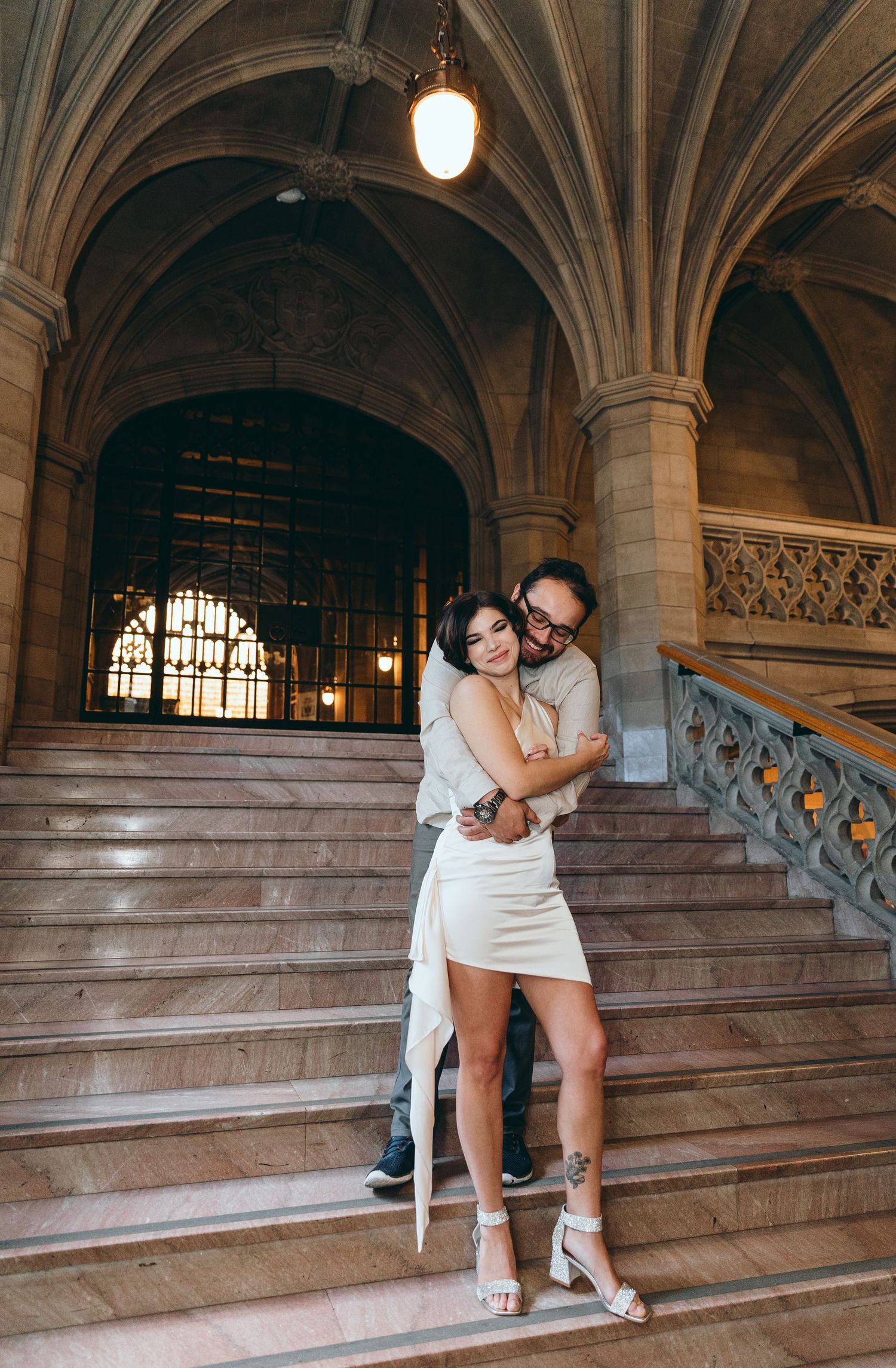 Romantic moment captured on ornate stone staircase in historic building interior.