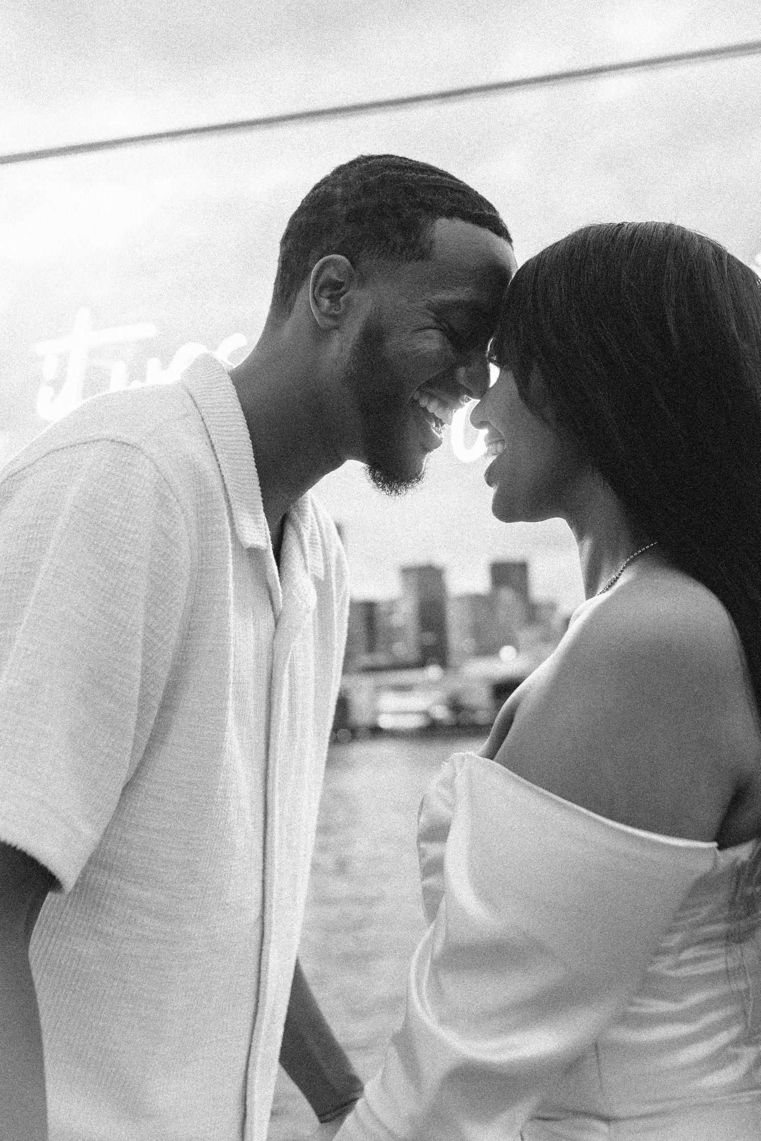 A couple shares an intimate moment against a waterfront backdrop.
