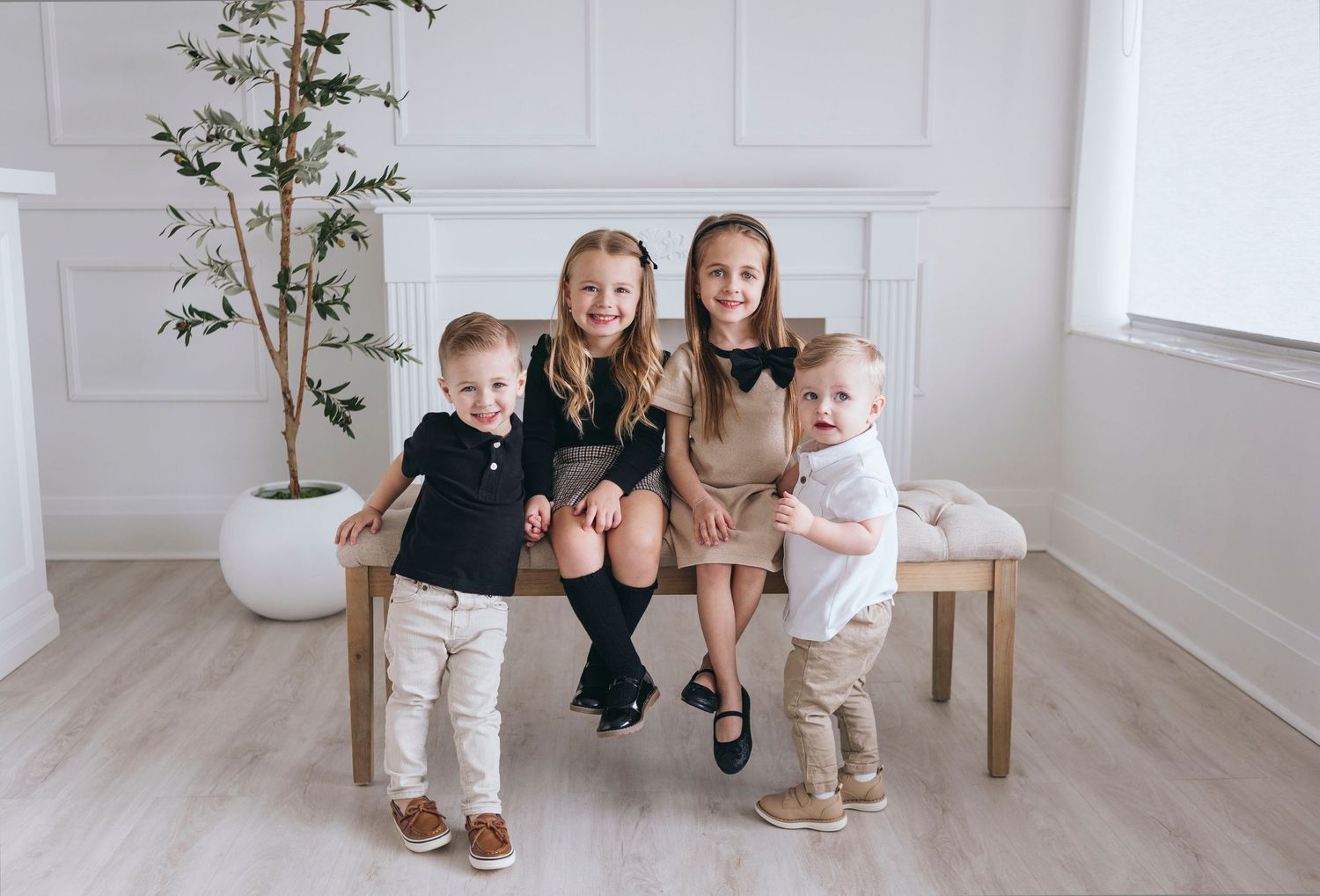 Family photo session in bright white studio with modern seating and botanical accents.