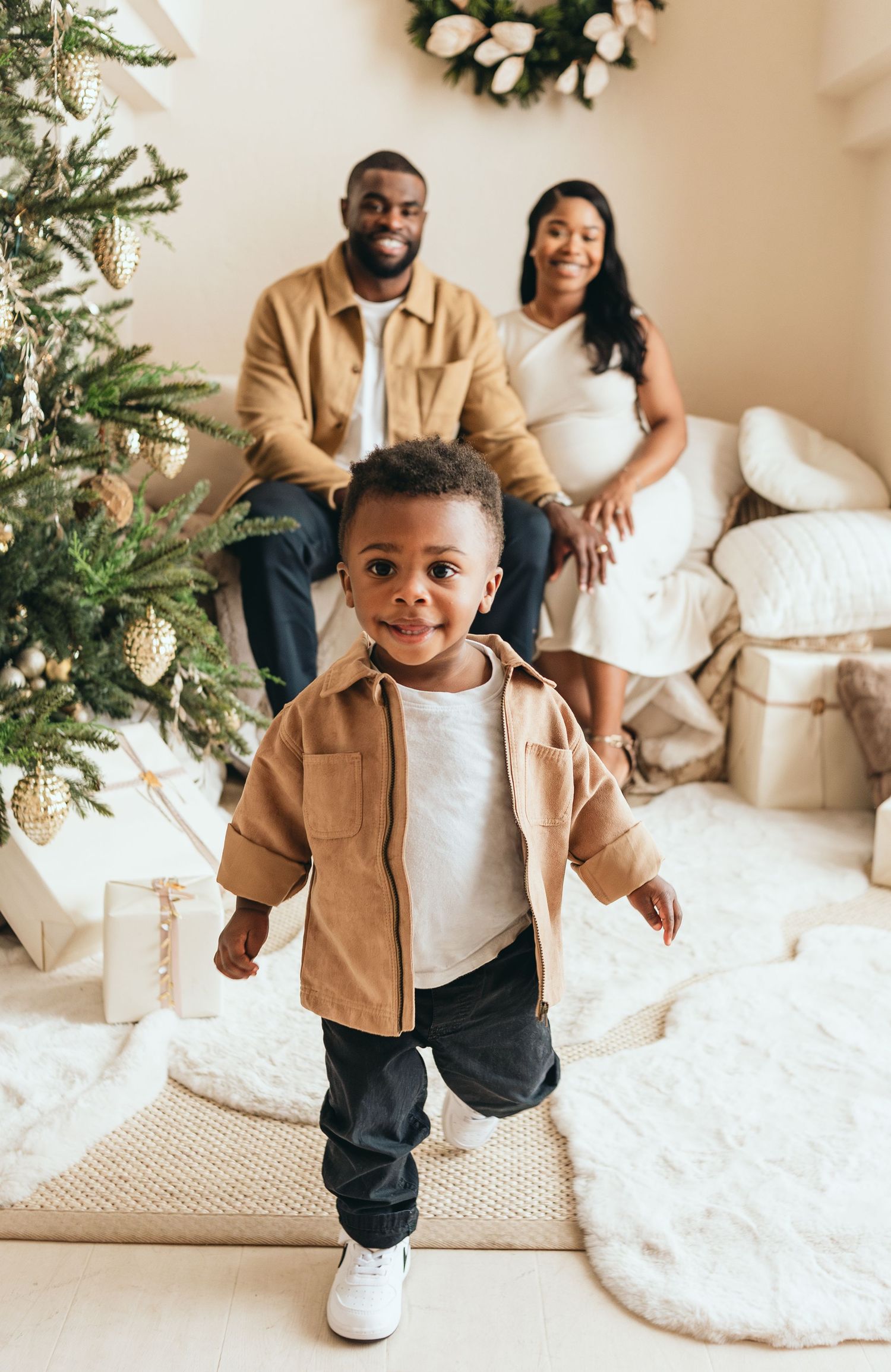 Joyful holiday family portrait with Christmas tree and wrapped presents in the background.