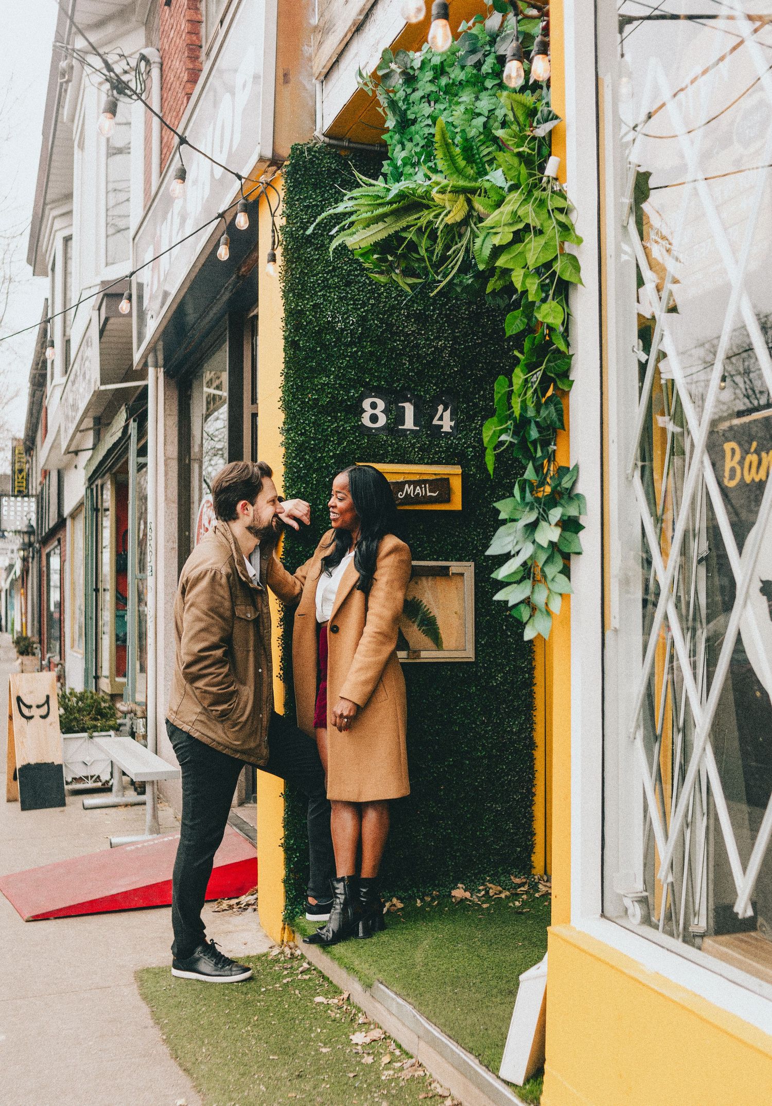 People entering a storefront with a yellow door and green wall decorations.