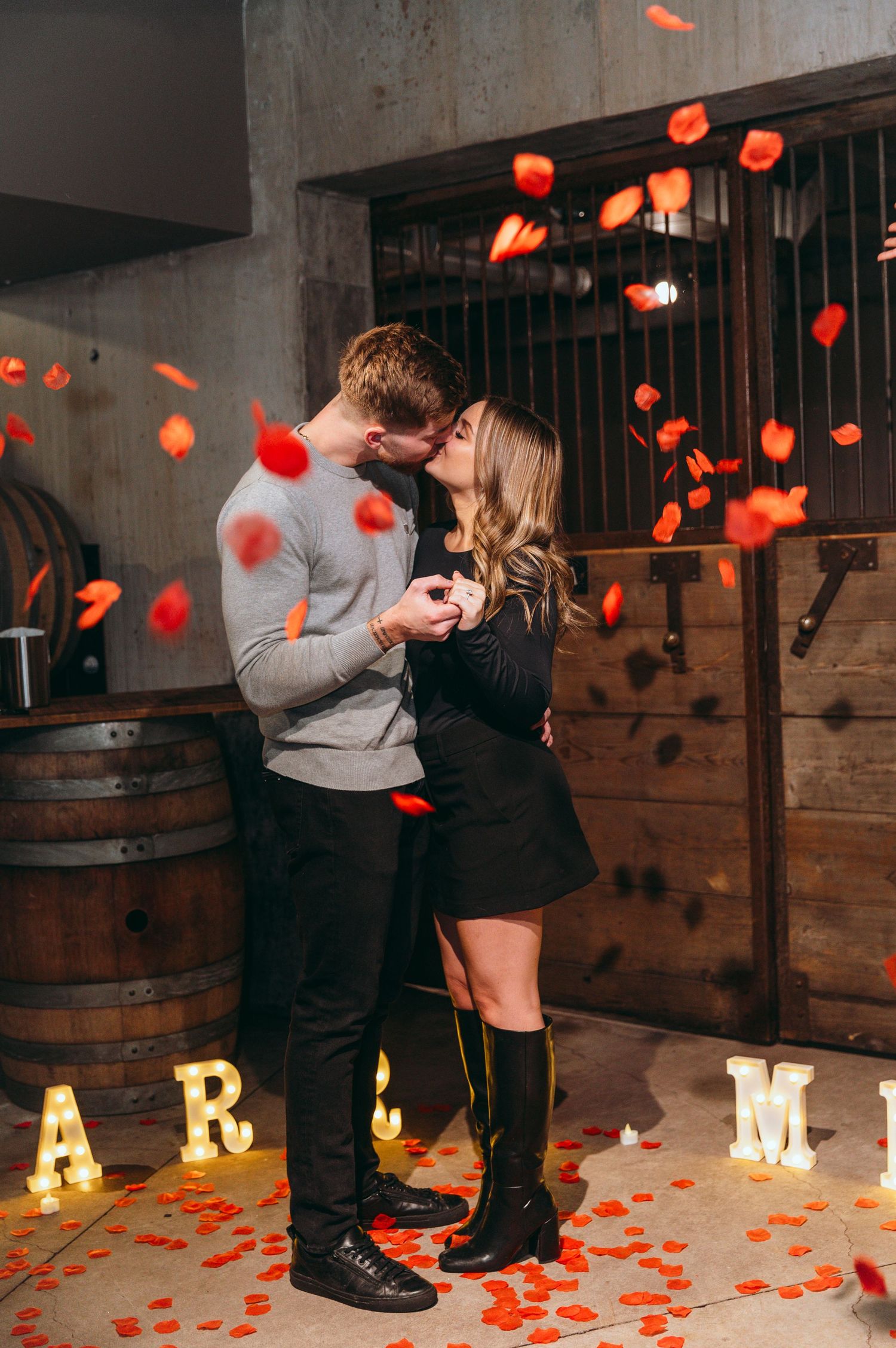 Romantic moment in industrial setting with red rose petals and ambient lighting.