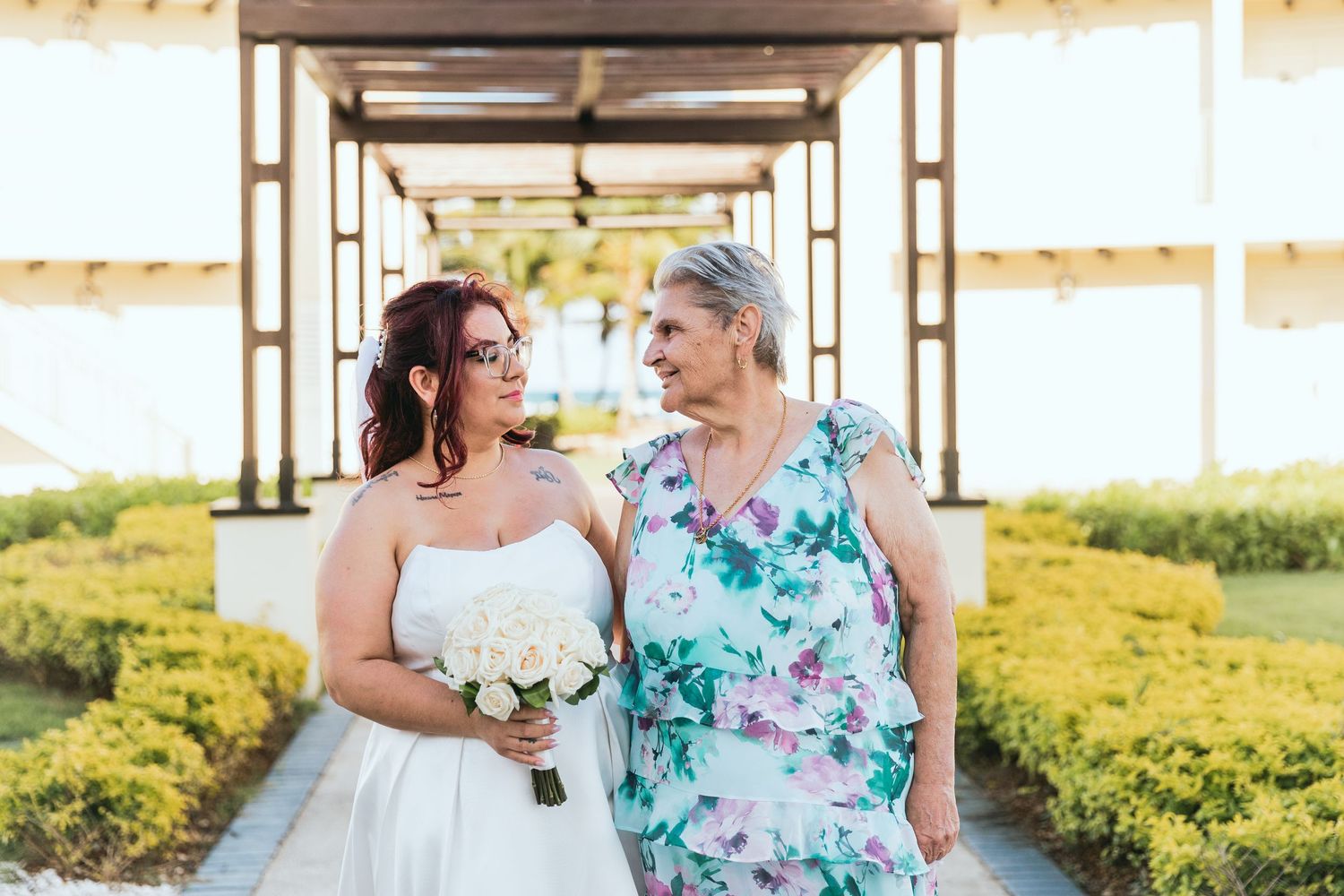 Wedding party members in floral dresses share joyful moments during outdoor photo session.