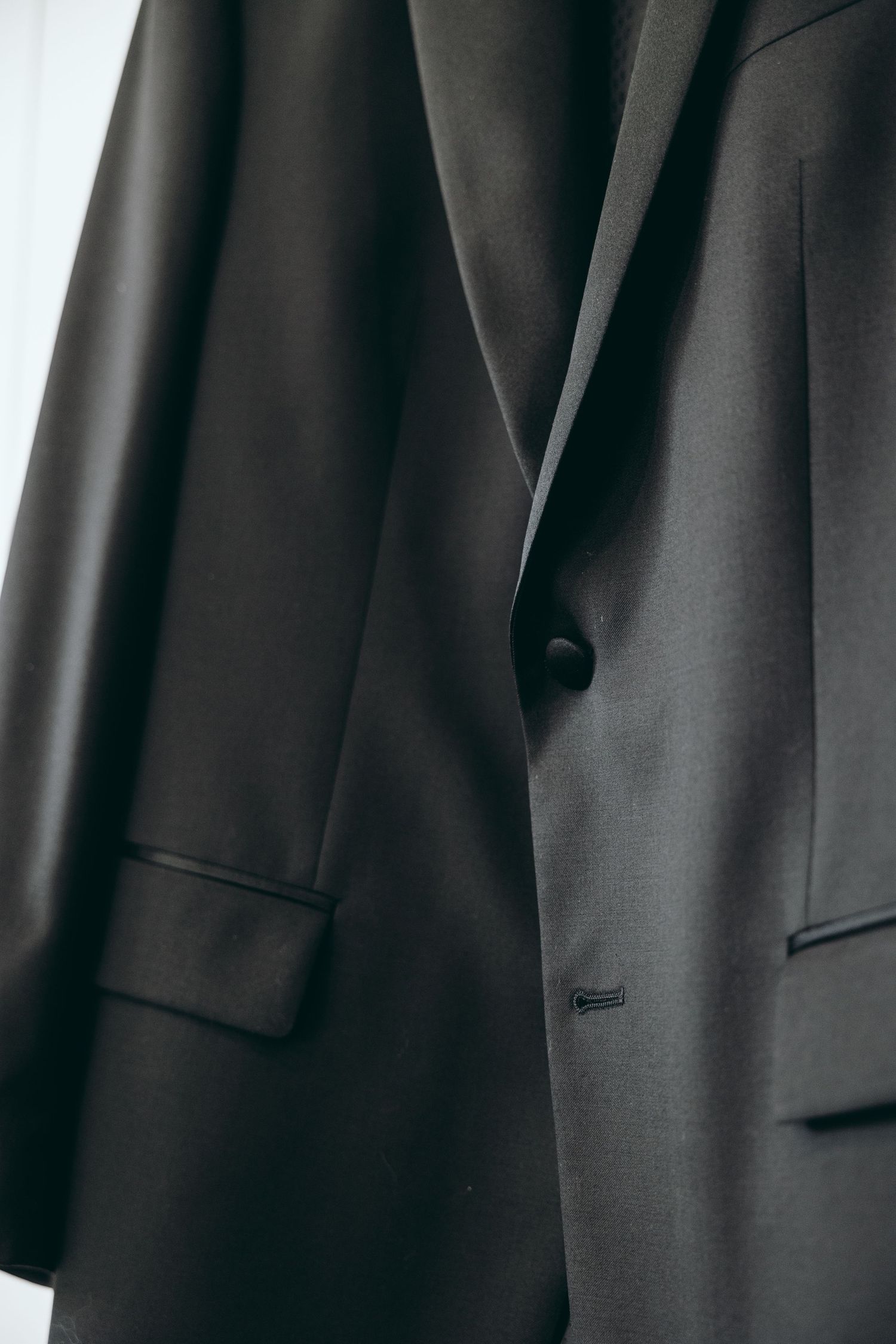 Close-up detail of a black formal suit jacket showing lapel and button.