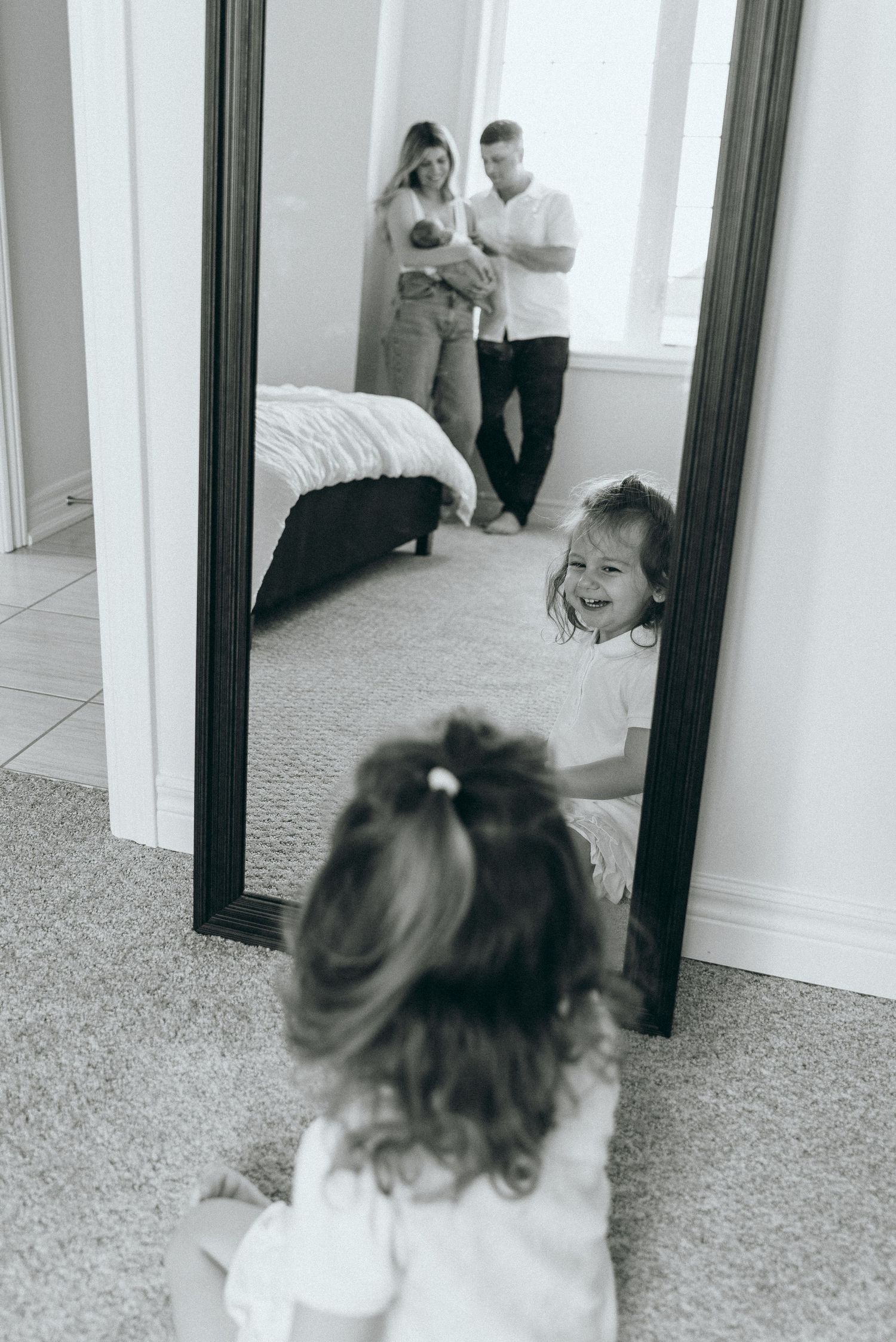 Black and white photos showing reflections in a mirror of intimate family moments.