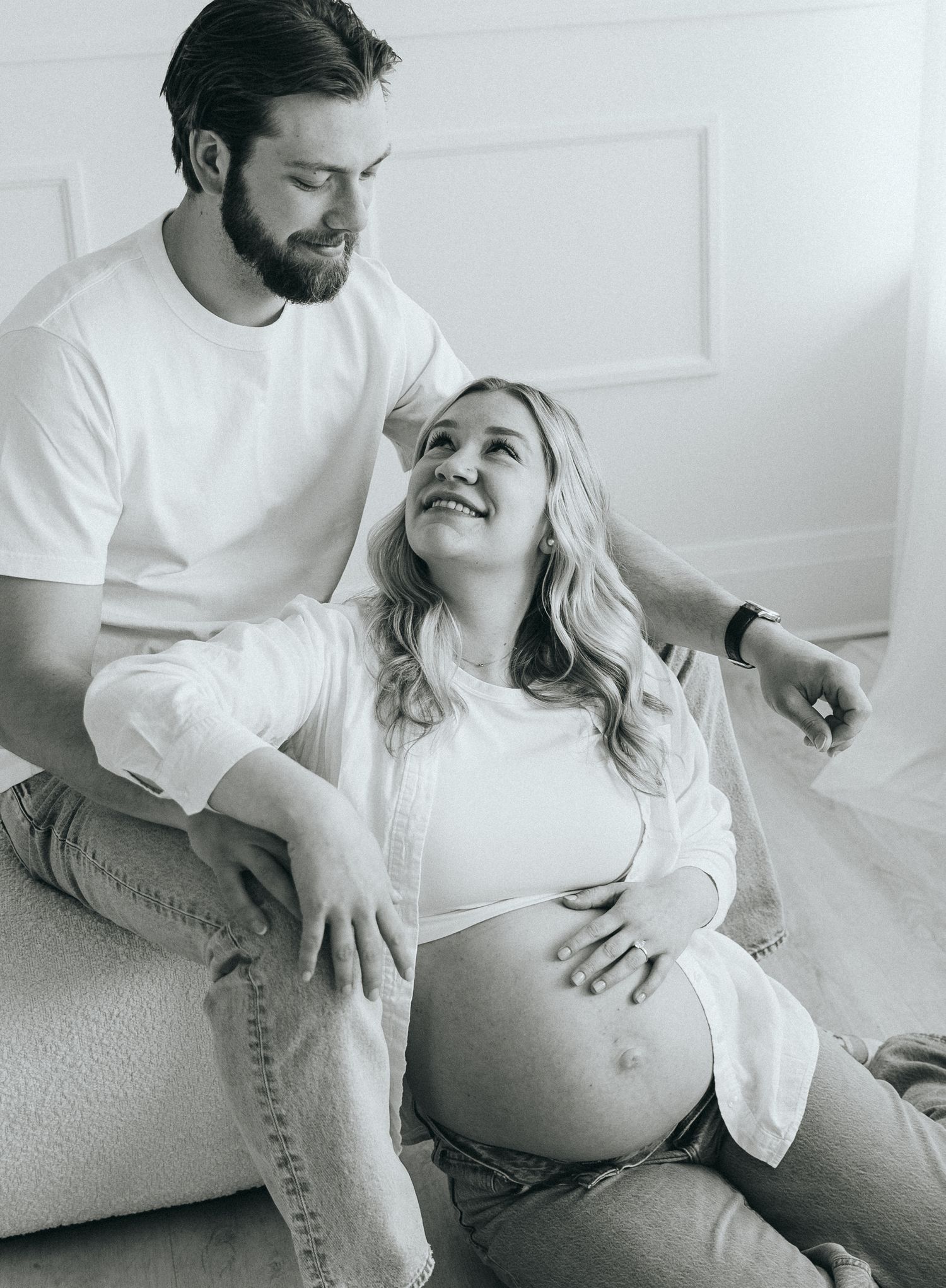 Black and white maternity photos capturing candid moments between couple.