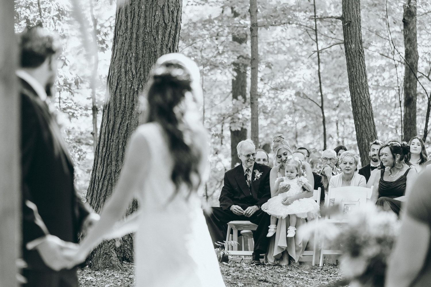 Black and white wedding ceremony photos taken in a serene forest setting.