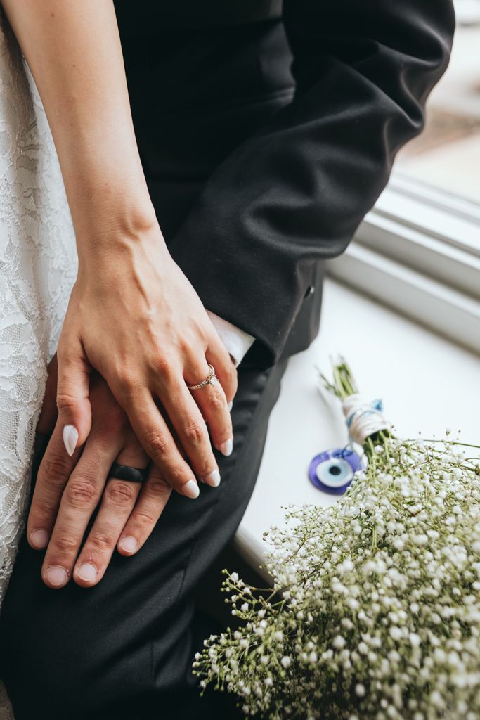 Close-up of hands and baby's breath bouquet against formal wedding attire.
