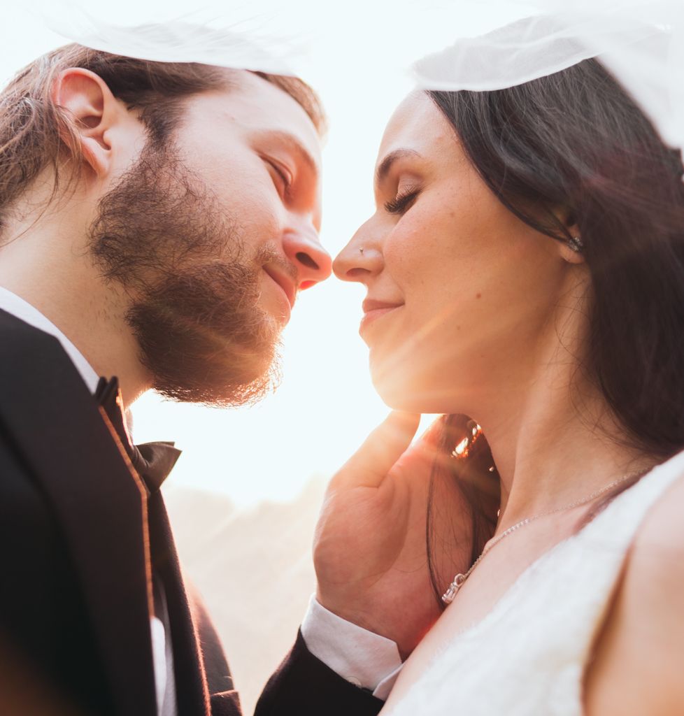 Close-up romantic portrait of a couple in wedding attire during sunset.