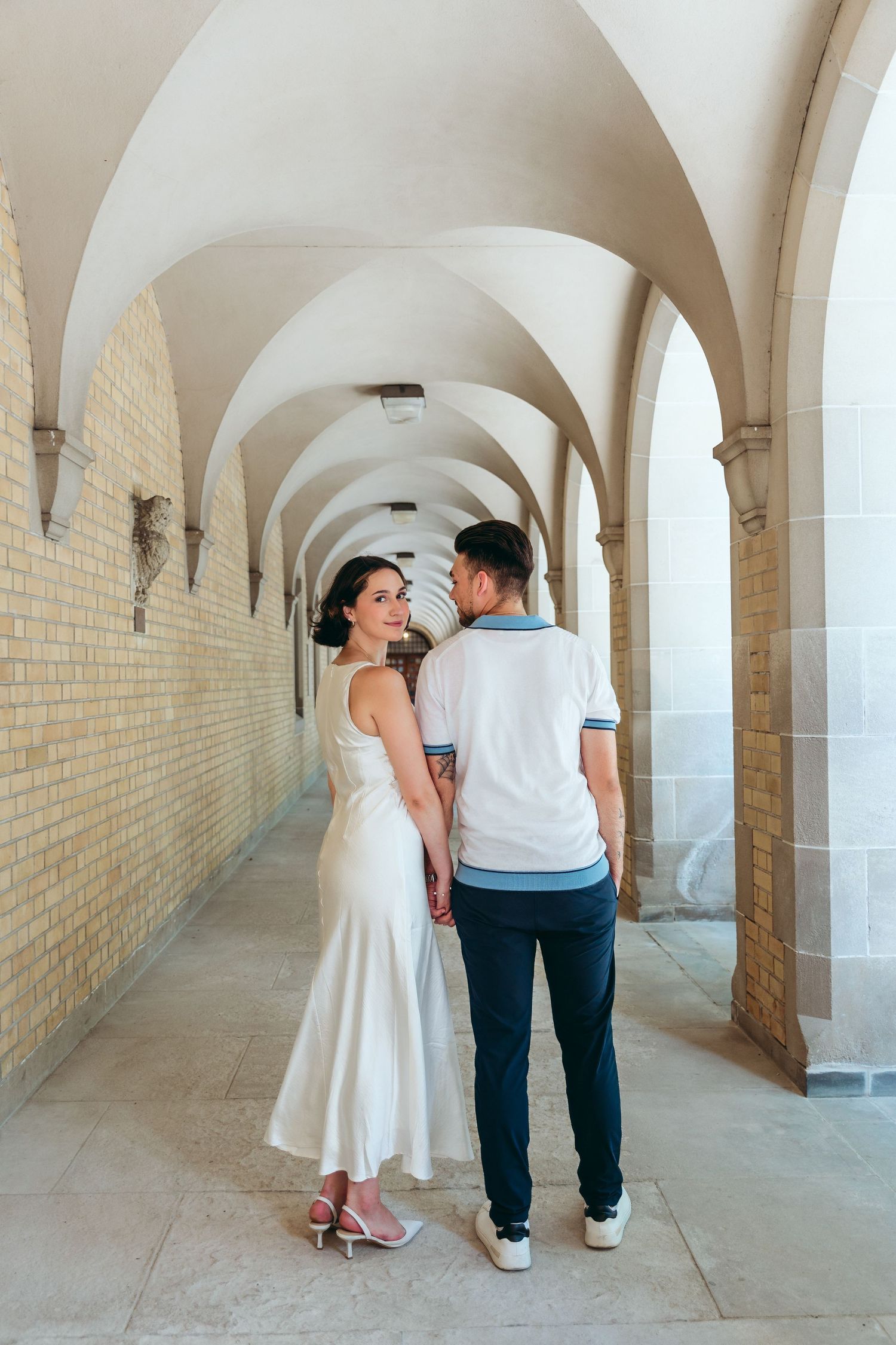 Intimate moment shared in historic arched hallway with cream colored walls.