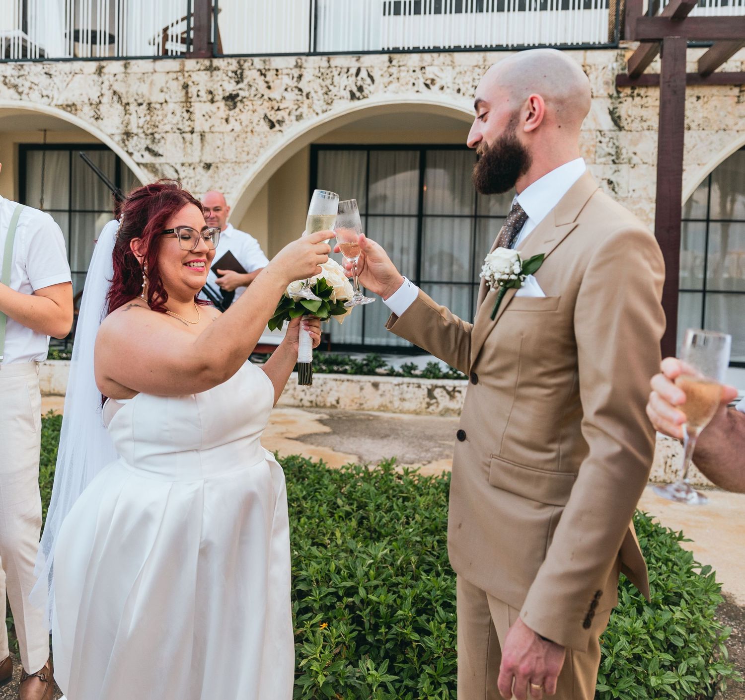 Wedding party dances and celebrates at a beachfront venue with tropical landscaping.