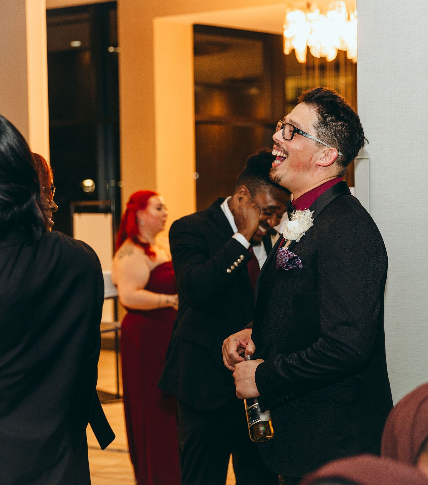 Wedding celebration in a warmly lit ballroom with guests dancing and socializing.
