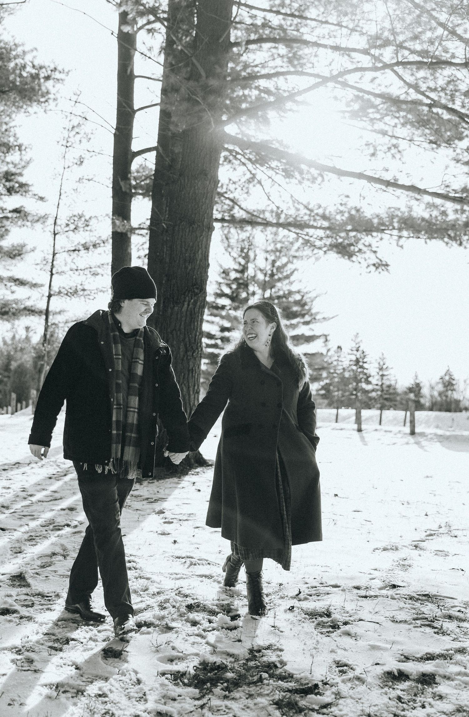 Black and white winter engagement photos captured in a snowy forest setting.