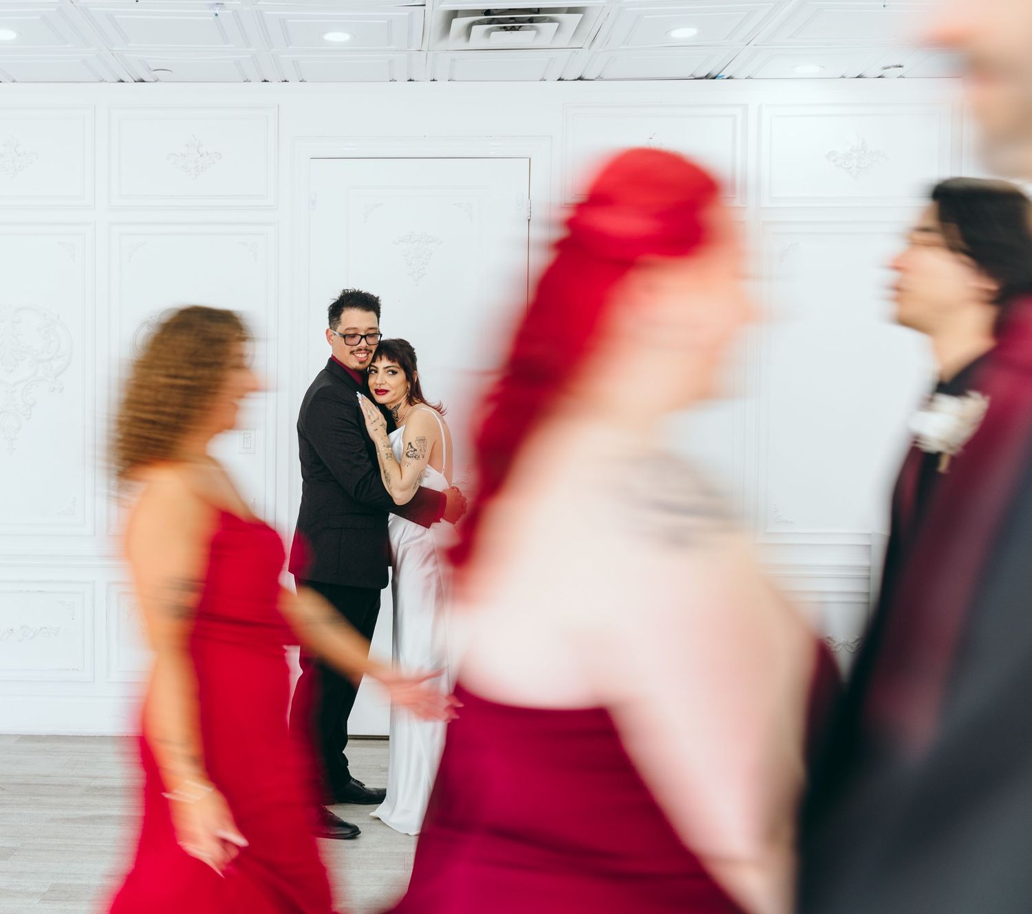 Blurred motion of wedding party dancing and moving in formal attire.