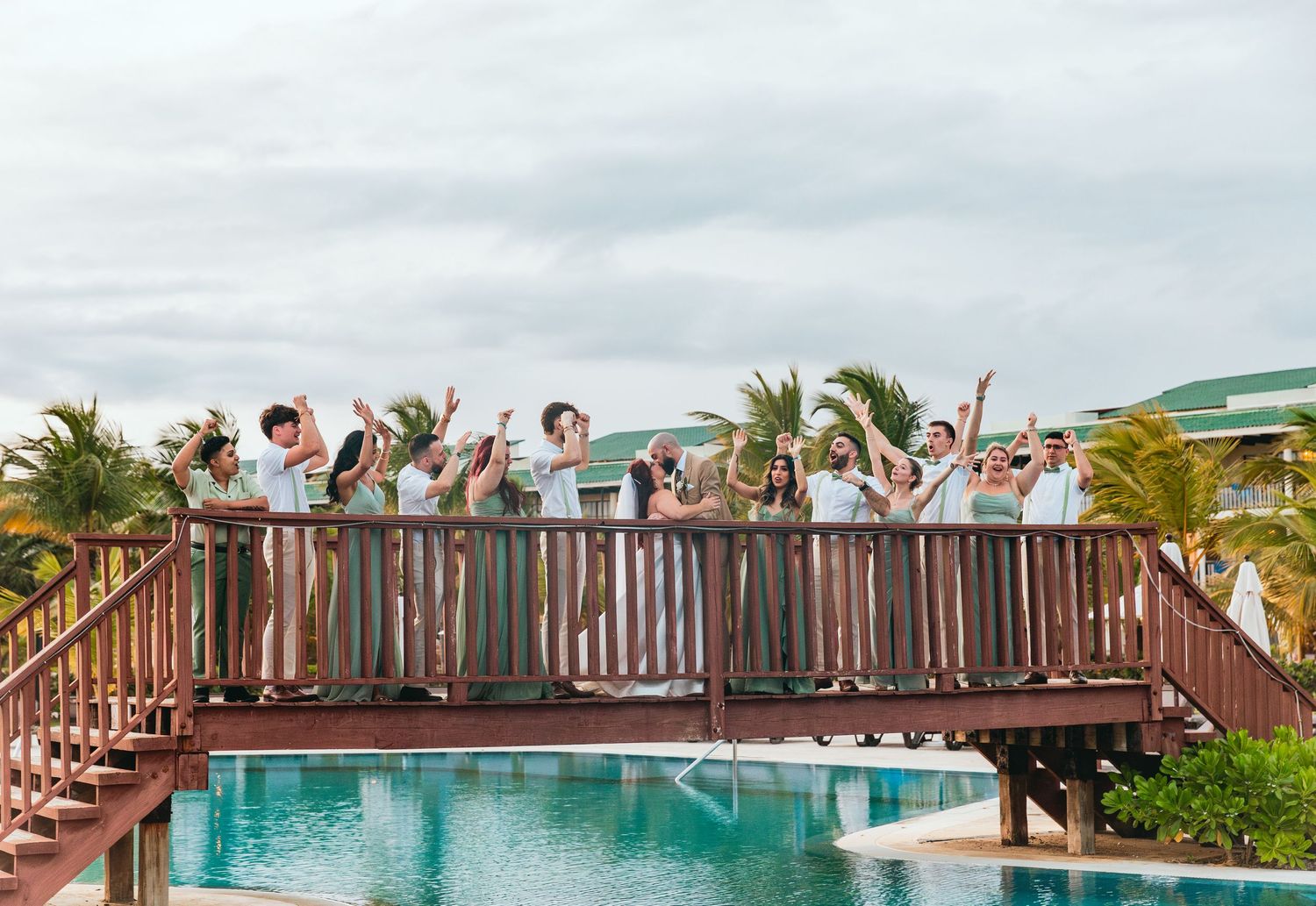 Wedding guests celebrate on a wooden deck overlooking the ocean.