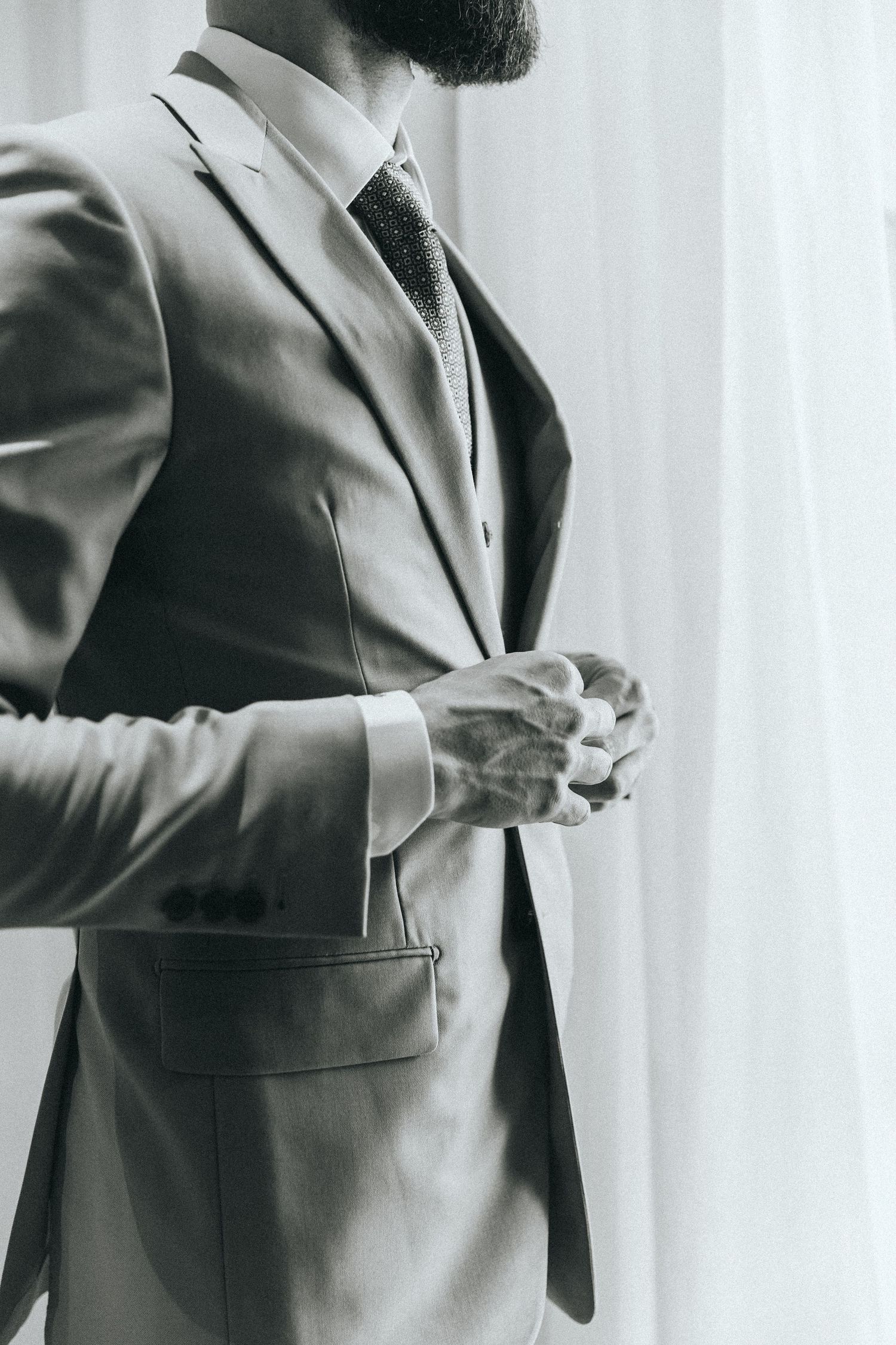 Side profile views of someone in a tan suit jacket gesturing while holding a beverage.