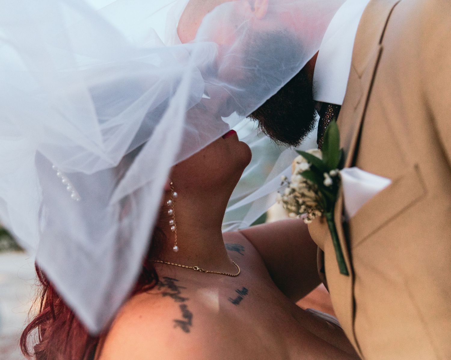 Close-up detail of white veil and boutonniere during wedding ceremony.