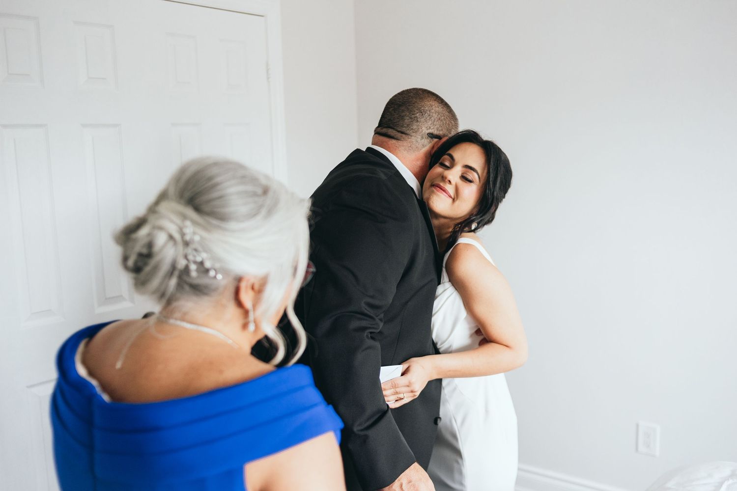 Three people sharing an intimate moment during a wedding celebration.