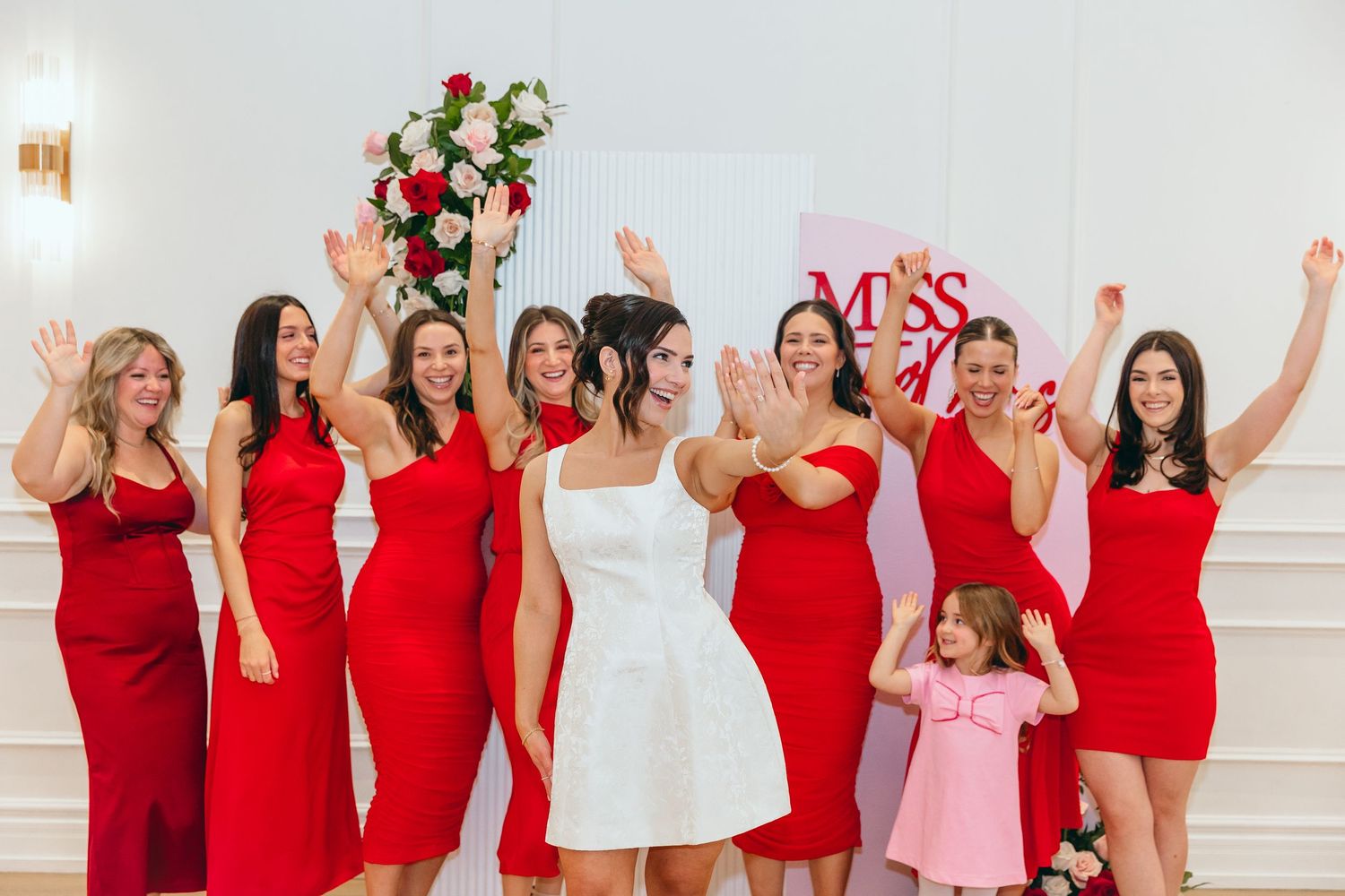 Bridesmaids in red dresses celebrating at a wedding event.
