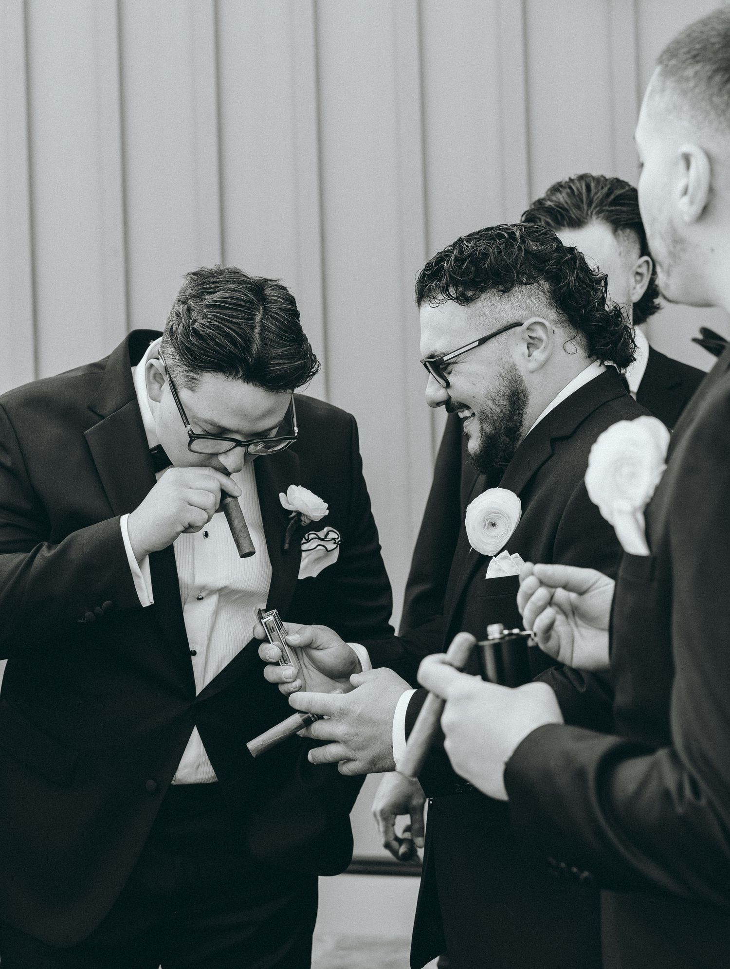 Groomsmen sharing a laugh together while getting ready in formal black tuxedos.