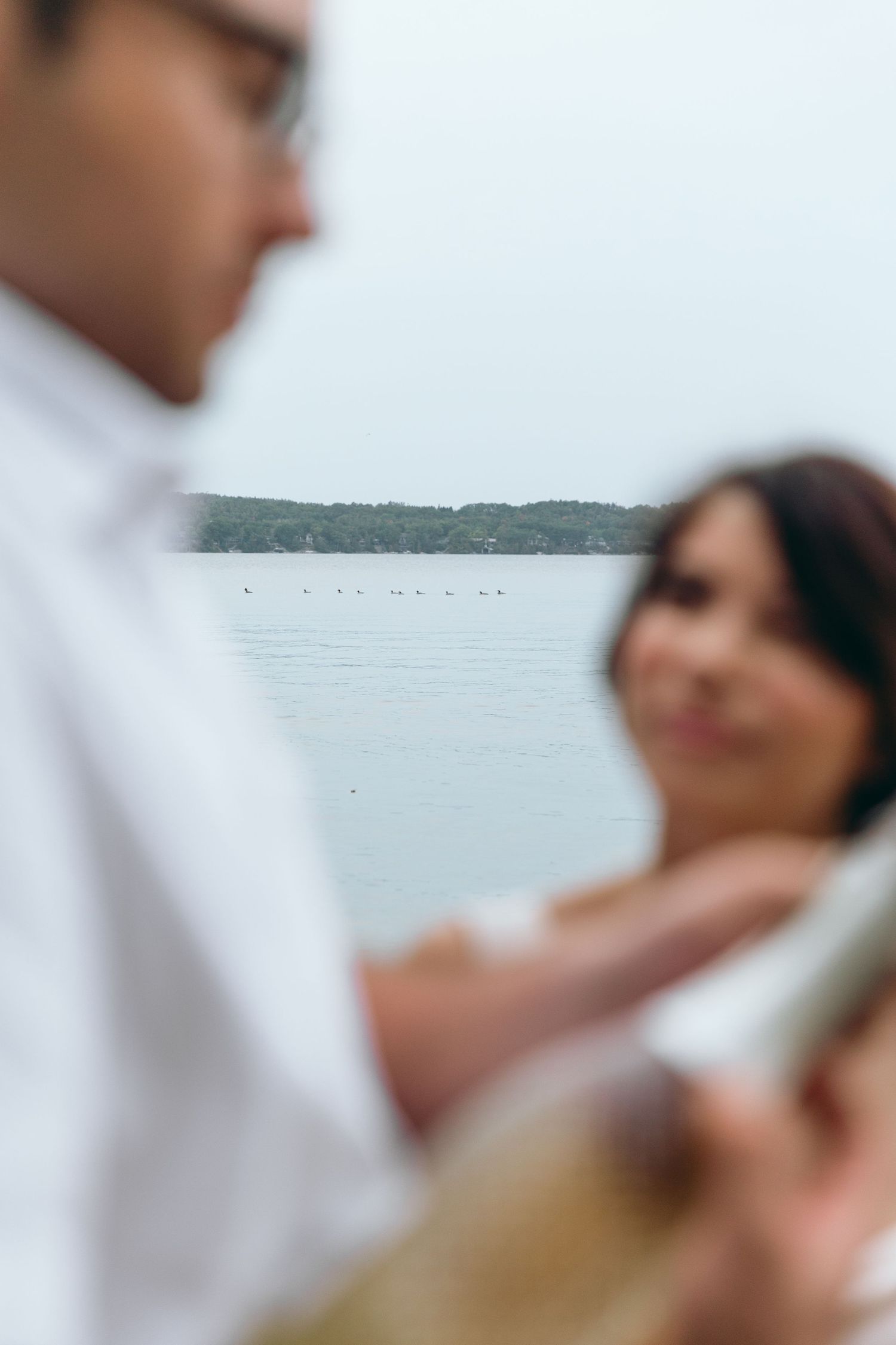 Blurred waterfront scene with couple in white clothing.