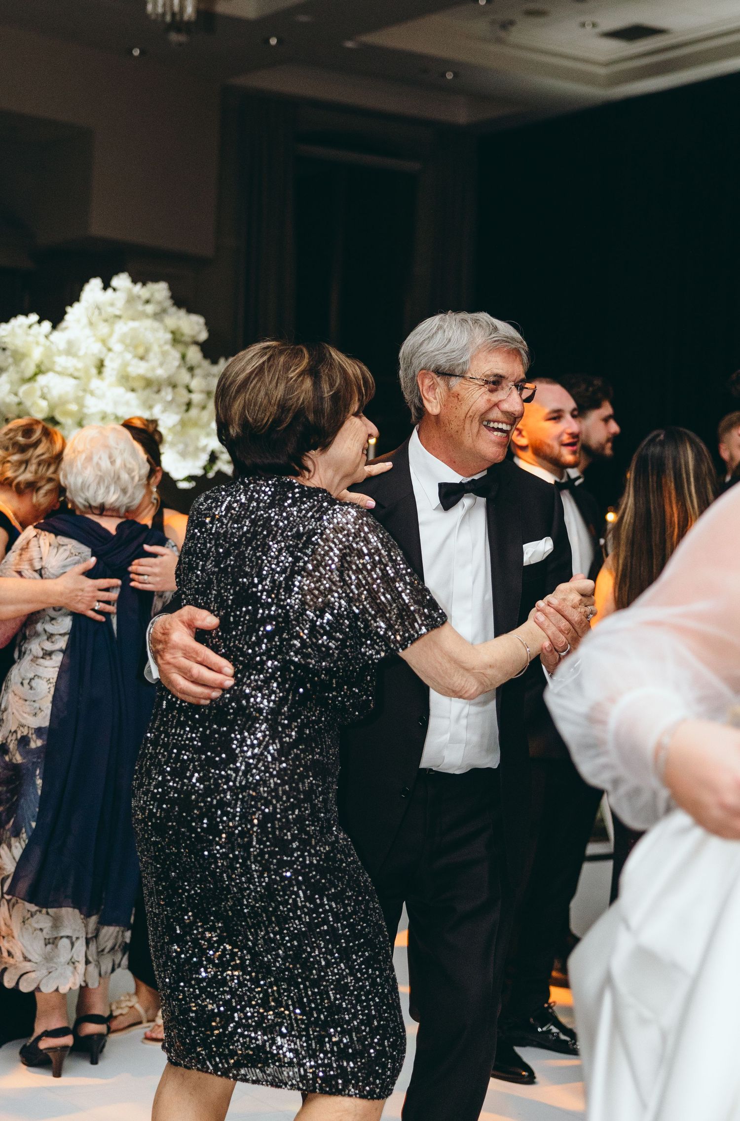 Wedding guests dance together on the dance floor during an elegant reception celebration.