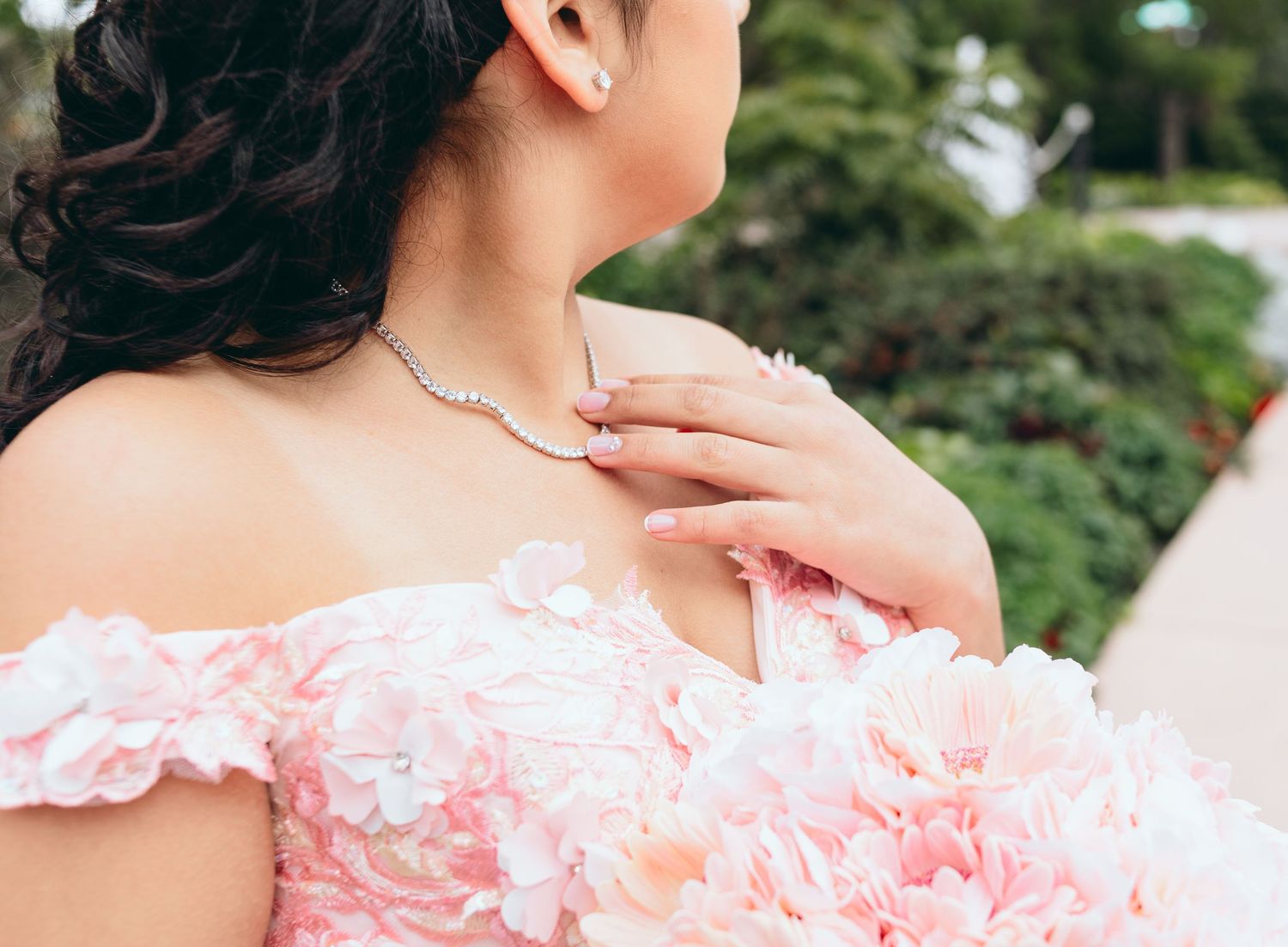 Close-up detail of a pink quinceanera dress with delicate lace and ruffled fabric details.