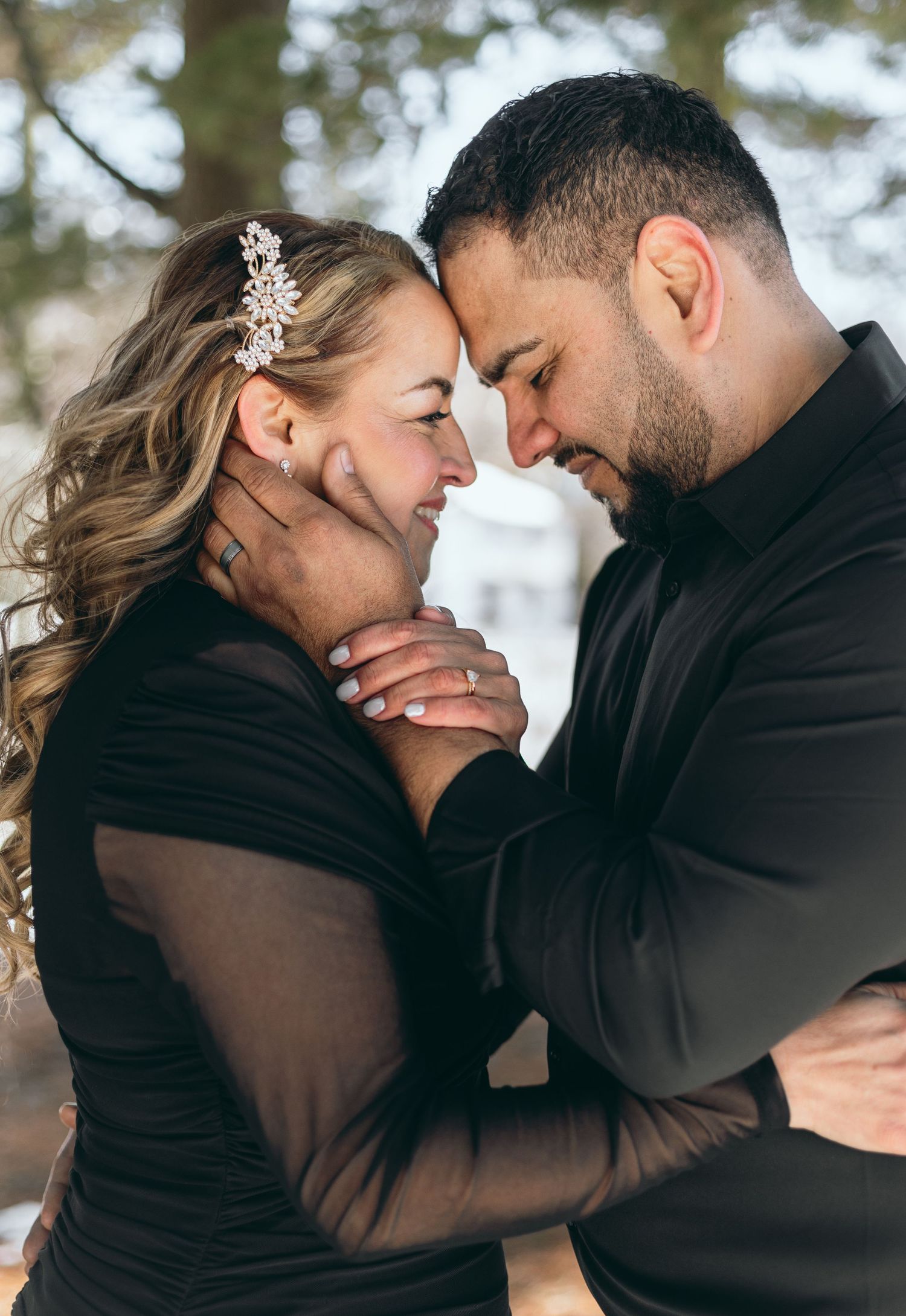 A romantic close-up portrait of a couple embracing outdoors.