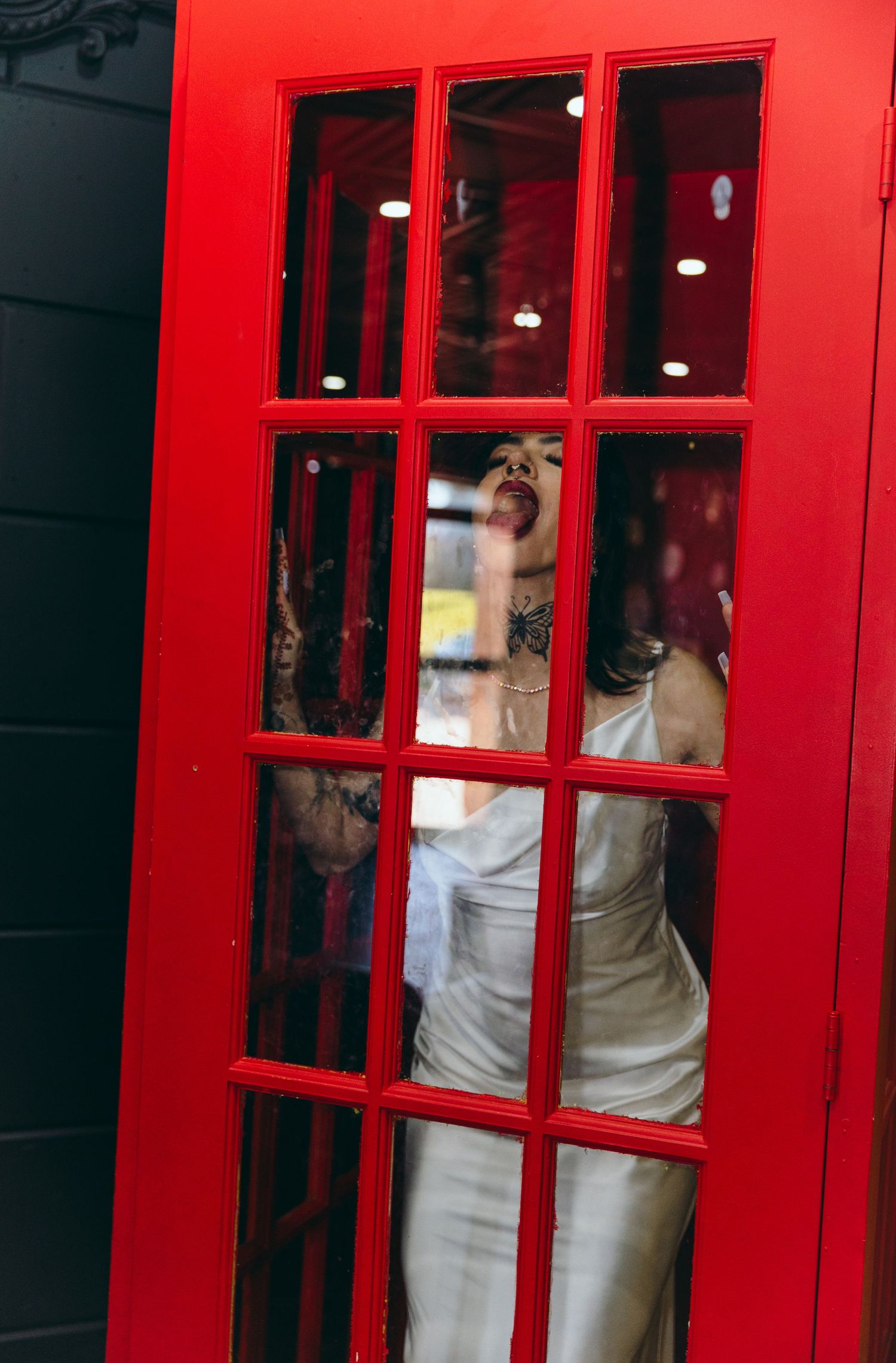 Bright red telephone booth frames wedding couple in formal attire.