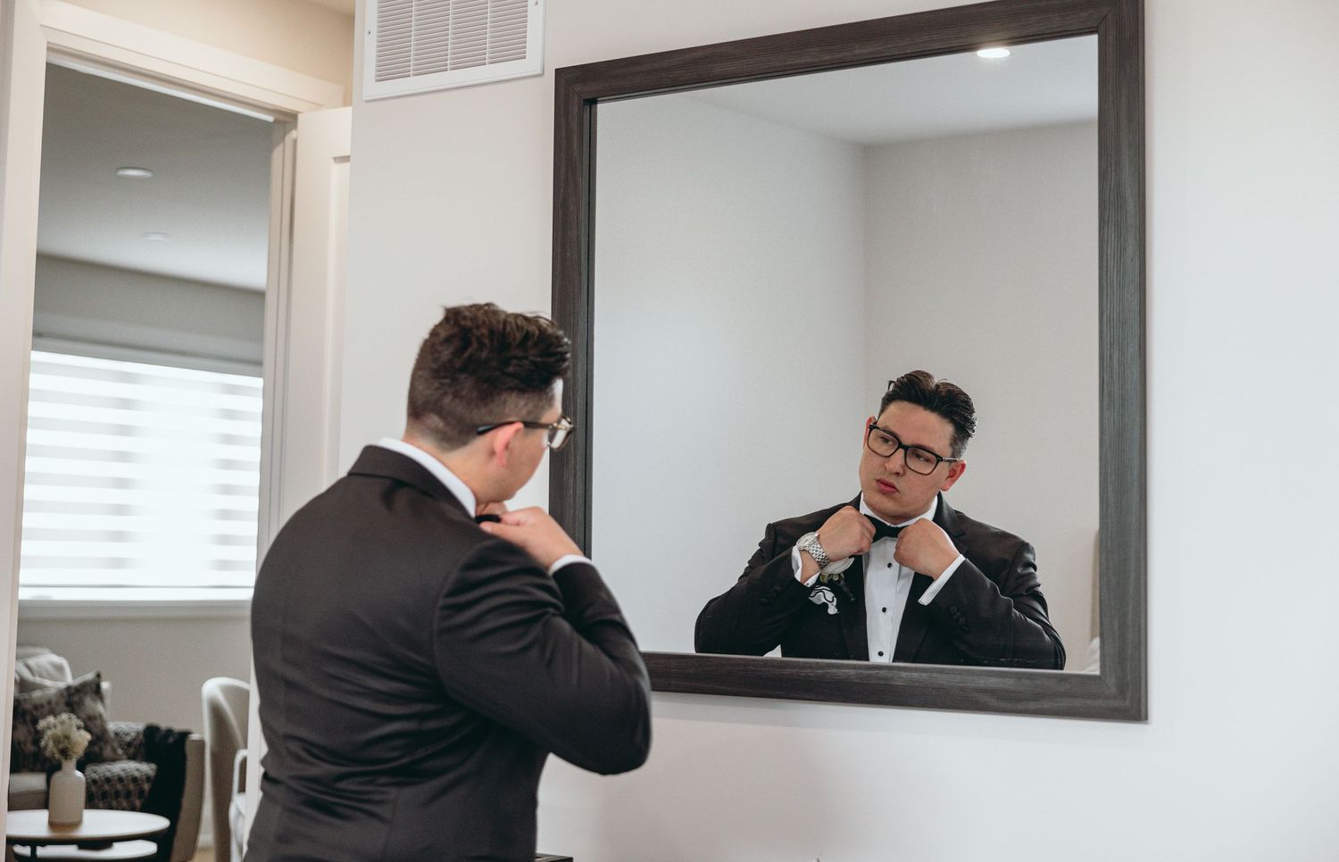 A sequence of mirror reflections showing someone adjusting formal attire in a modern room.