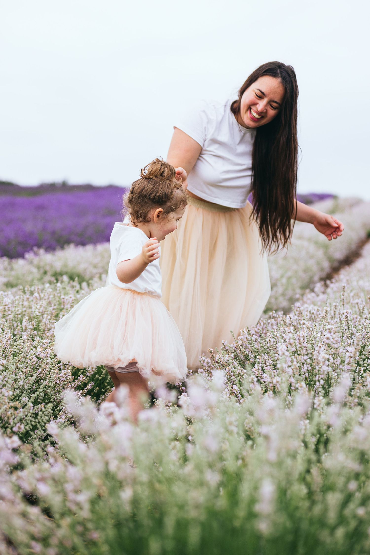 Family walking through a blooming lavender field wearing white and cream colored outfits.