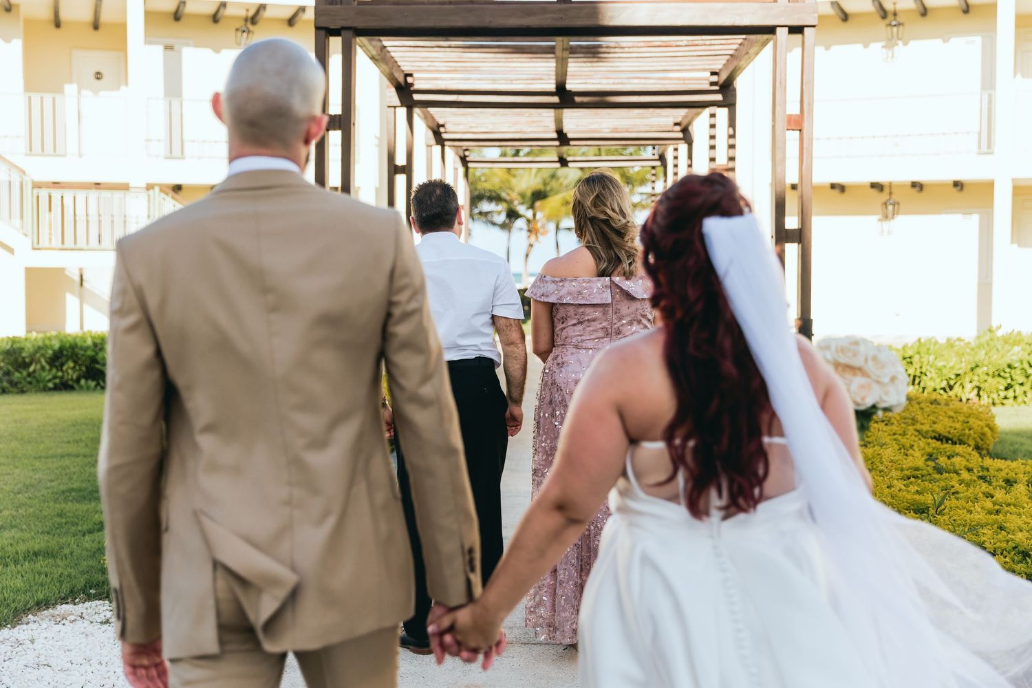 Wedding couple walking together along covered outdoor corridor.