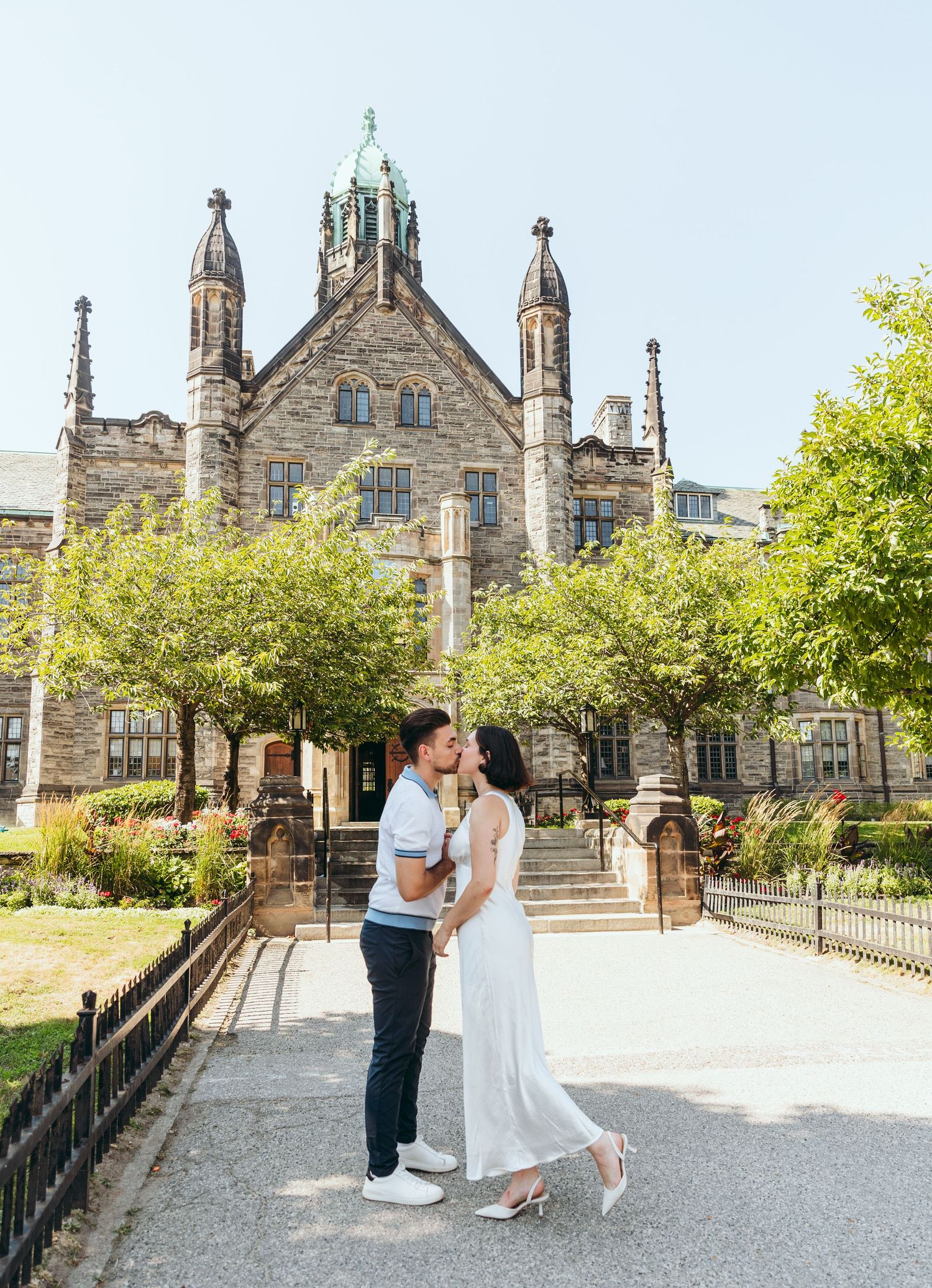 Elegant couple shares a tender moment on the grounds of a gothic stone cathedral.