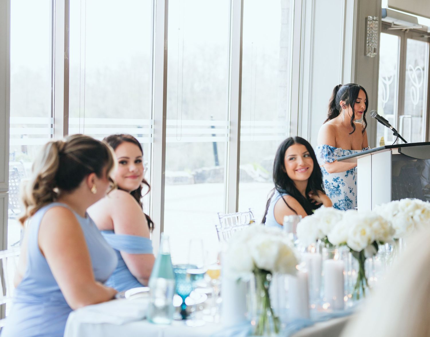 Elegant reception venue with white floral centerpieces and blue table settings.